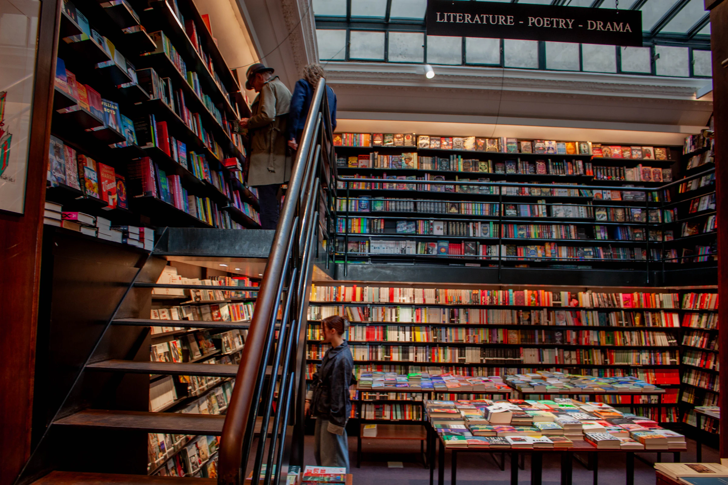 Personas recorriendo una librería real entre estanterías llenas de libros