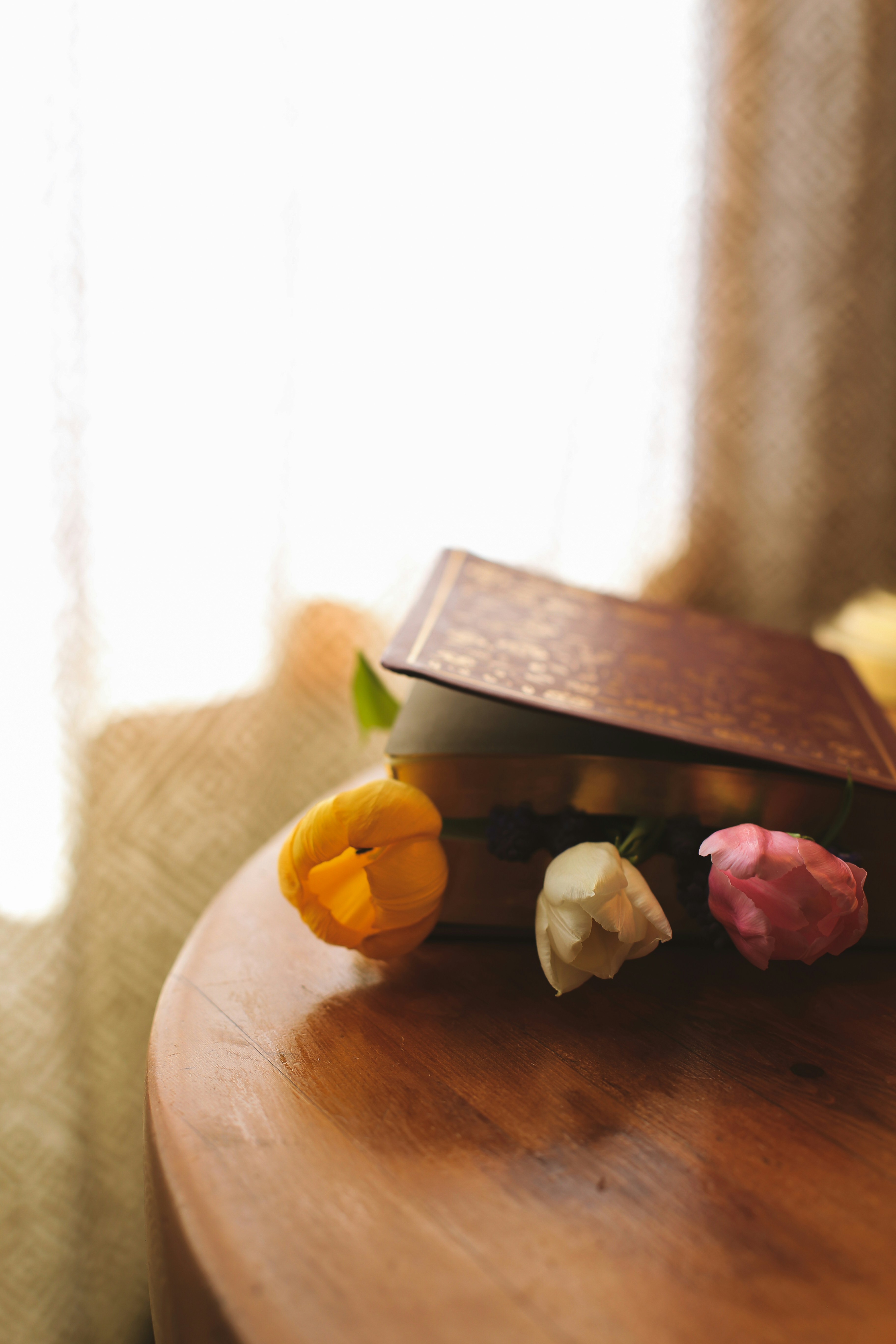 A closed book with colorful flowers on a wooden table.