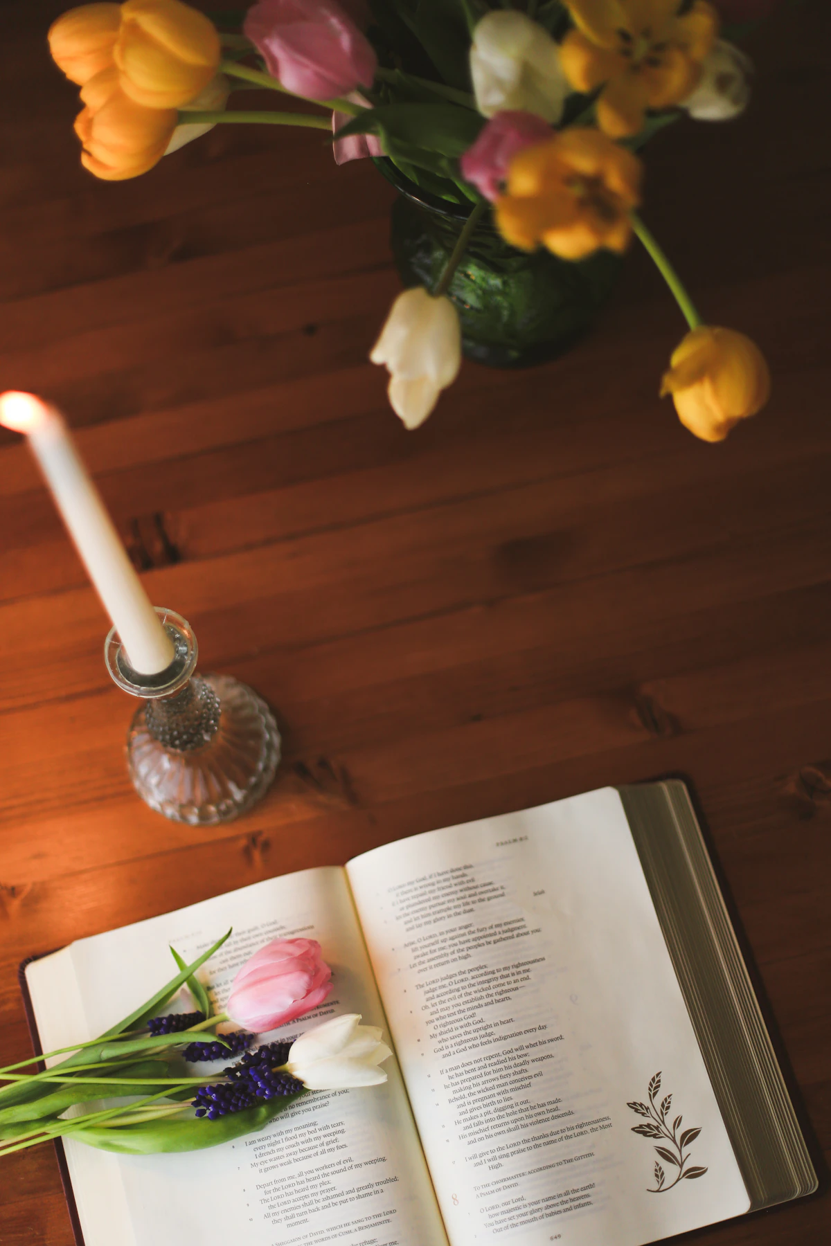 Kerze und Blumen neben einem geöffneten Buch als Symbol für Trost und Erinnerung bei Trauer