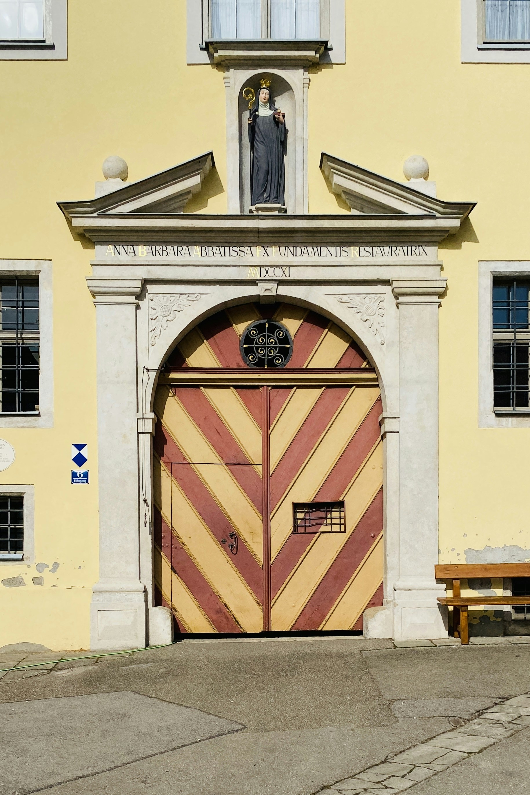 Ornate wooden doors on a yellow building with statue.