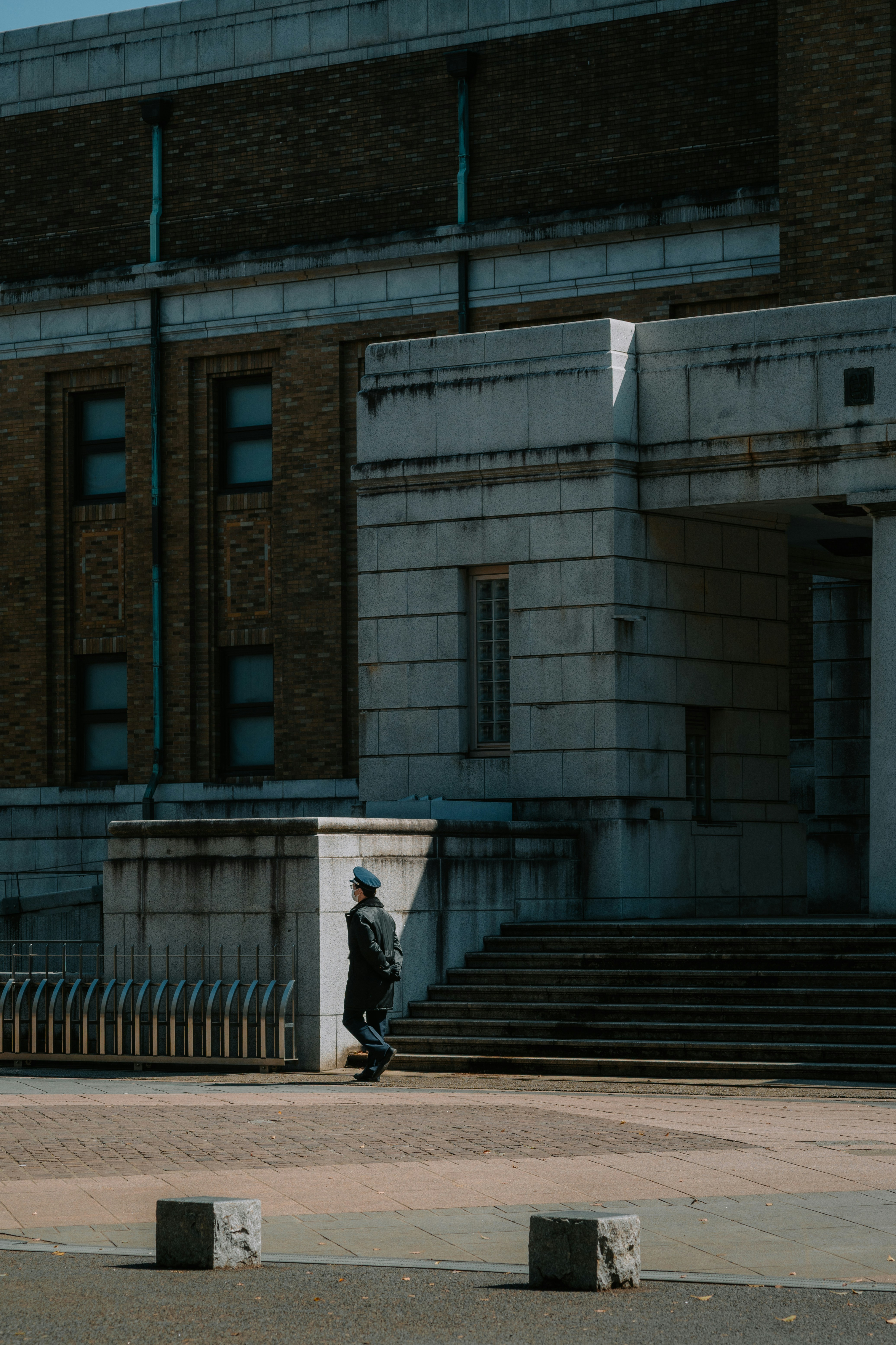 A person walks past a modern building with stairs.