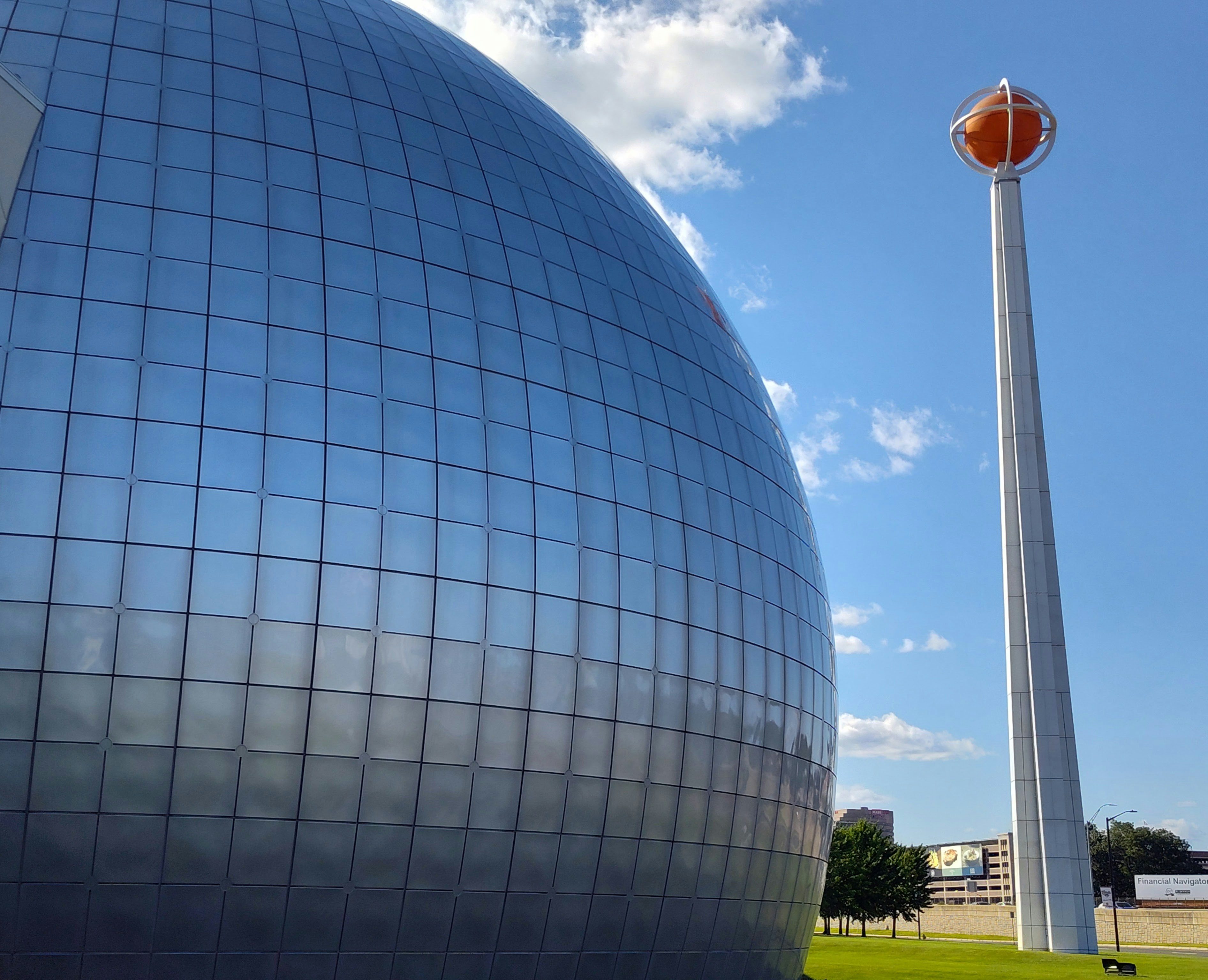 Modern domed building with tall tower against blue sky