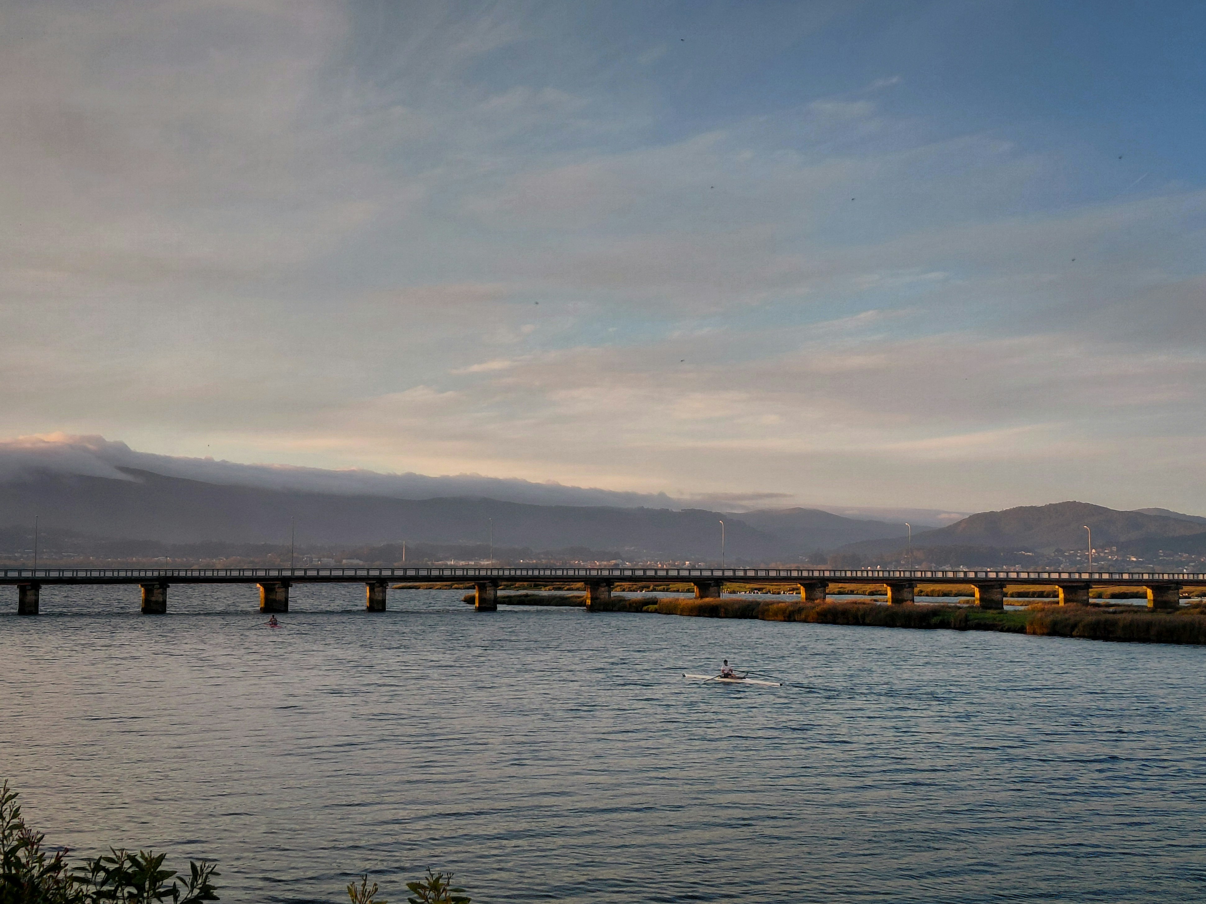 Bridge over a wide river with mountains in background.