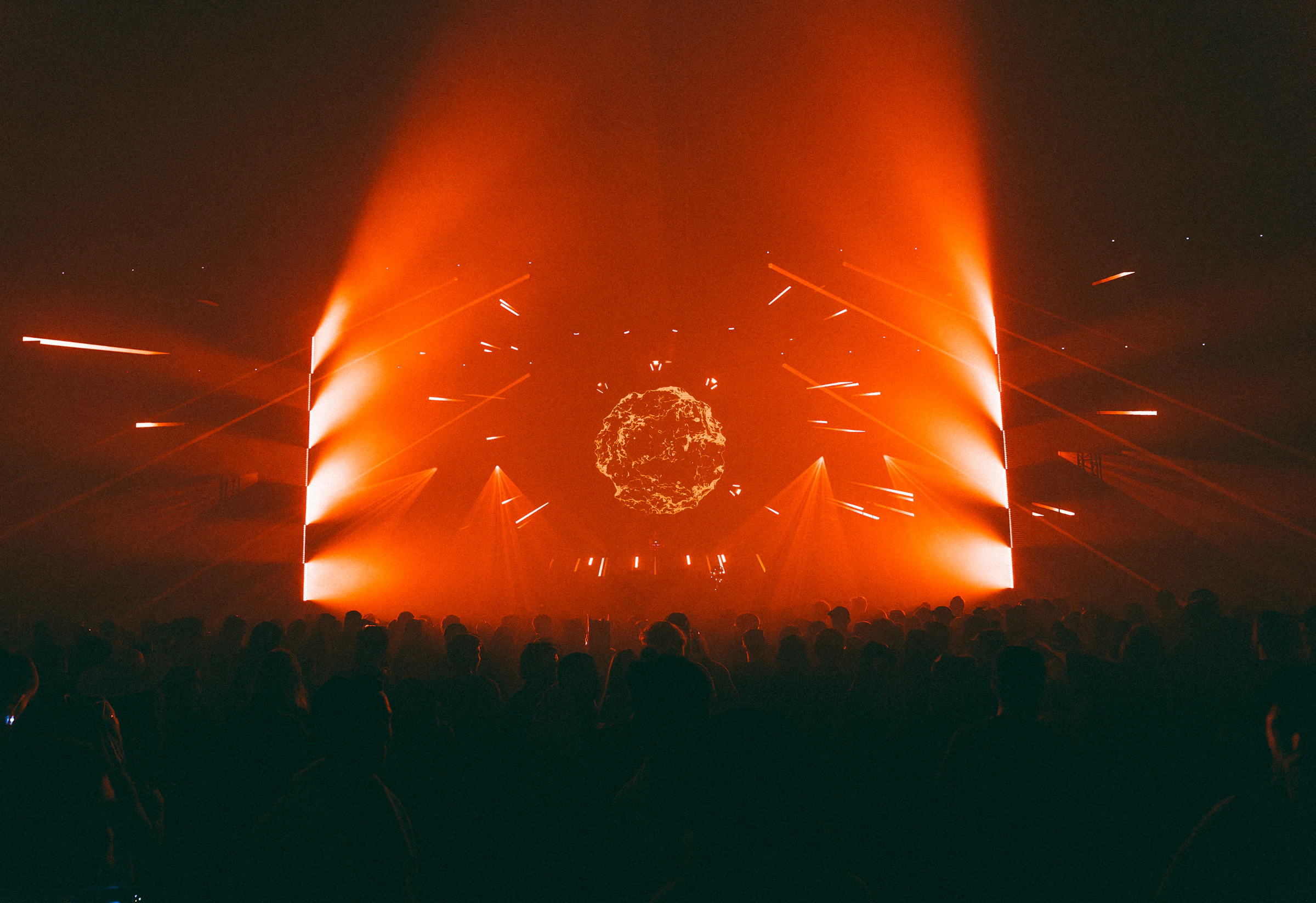Bright orange stage lights illuminating a festival crowd