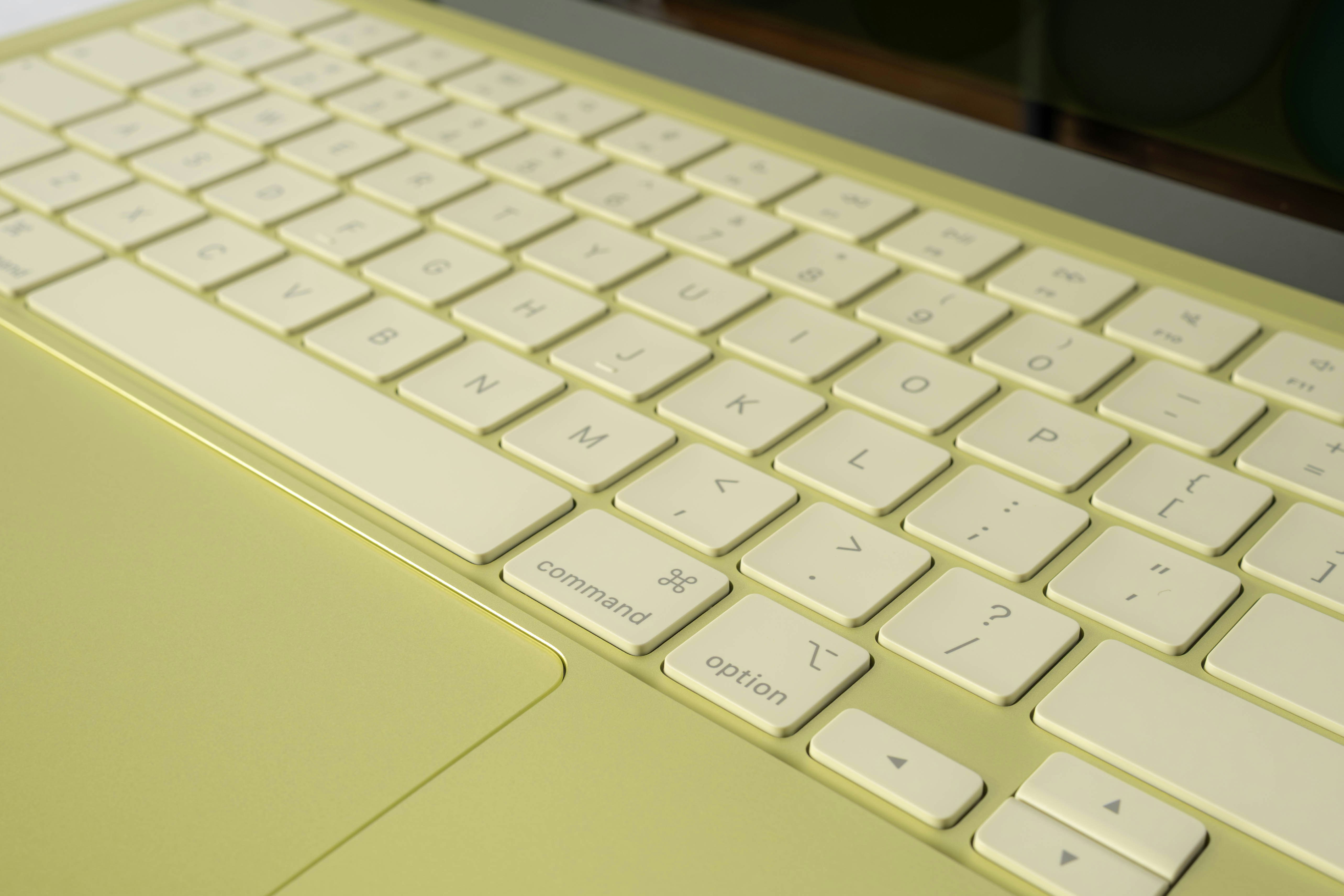 Close-up of a pale yellow computer keyboard and trackpad.