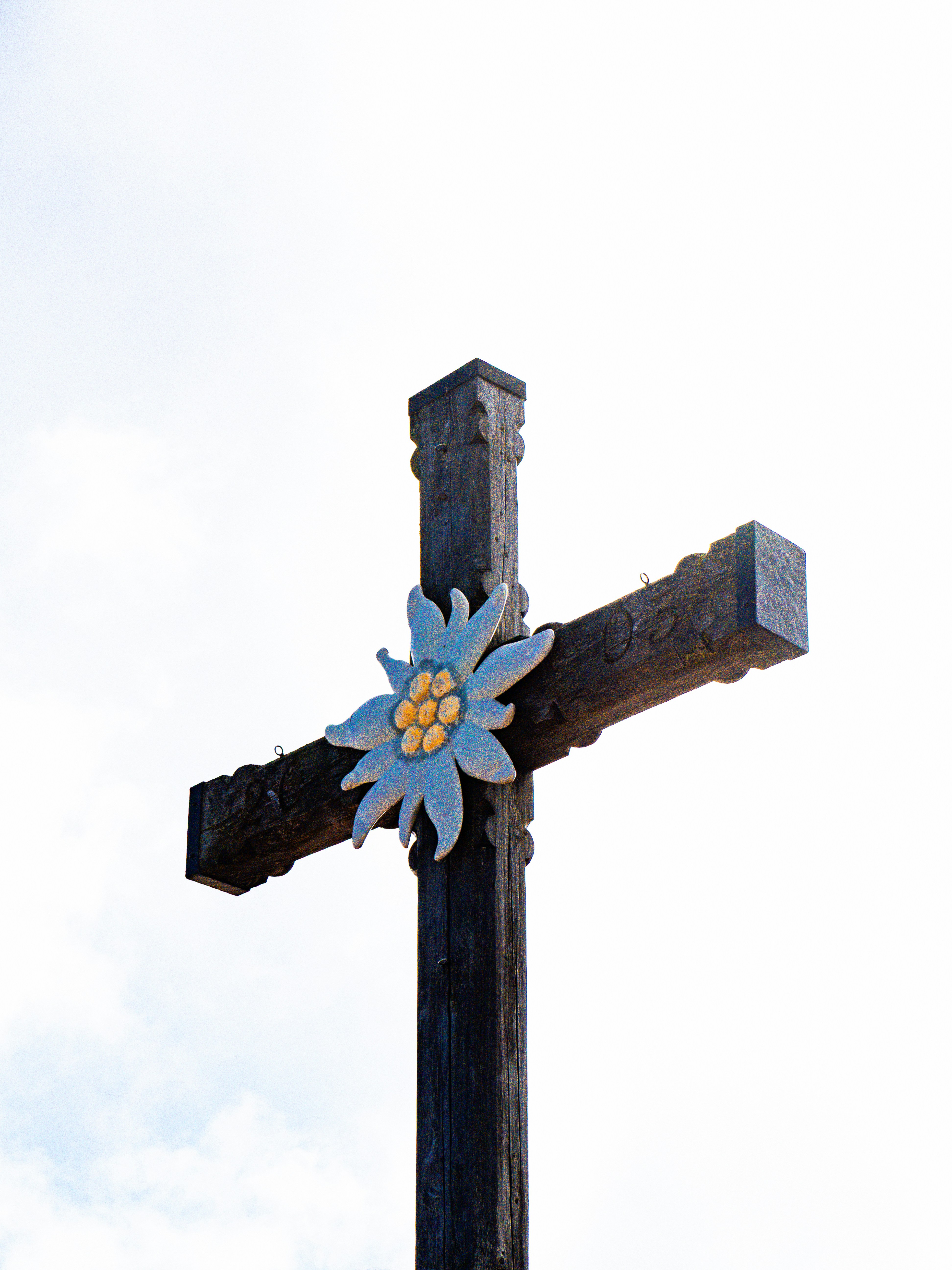 Wooden cross with edelweiss flower against sky
