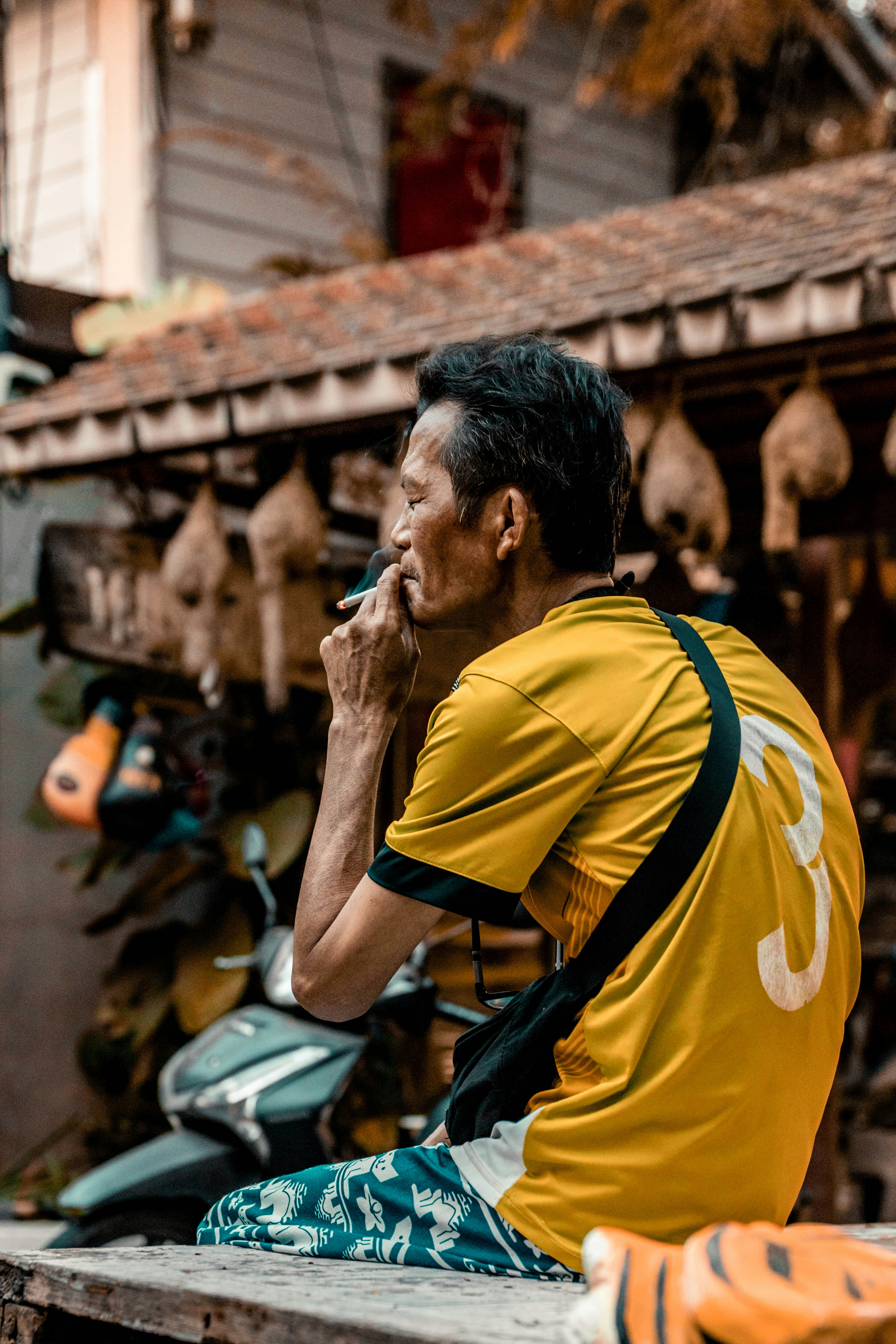 Mann im gelben Hemd raucht draußen