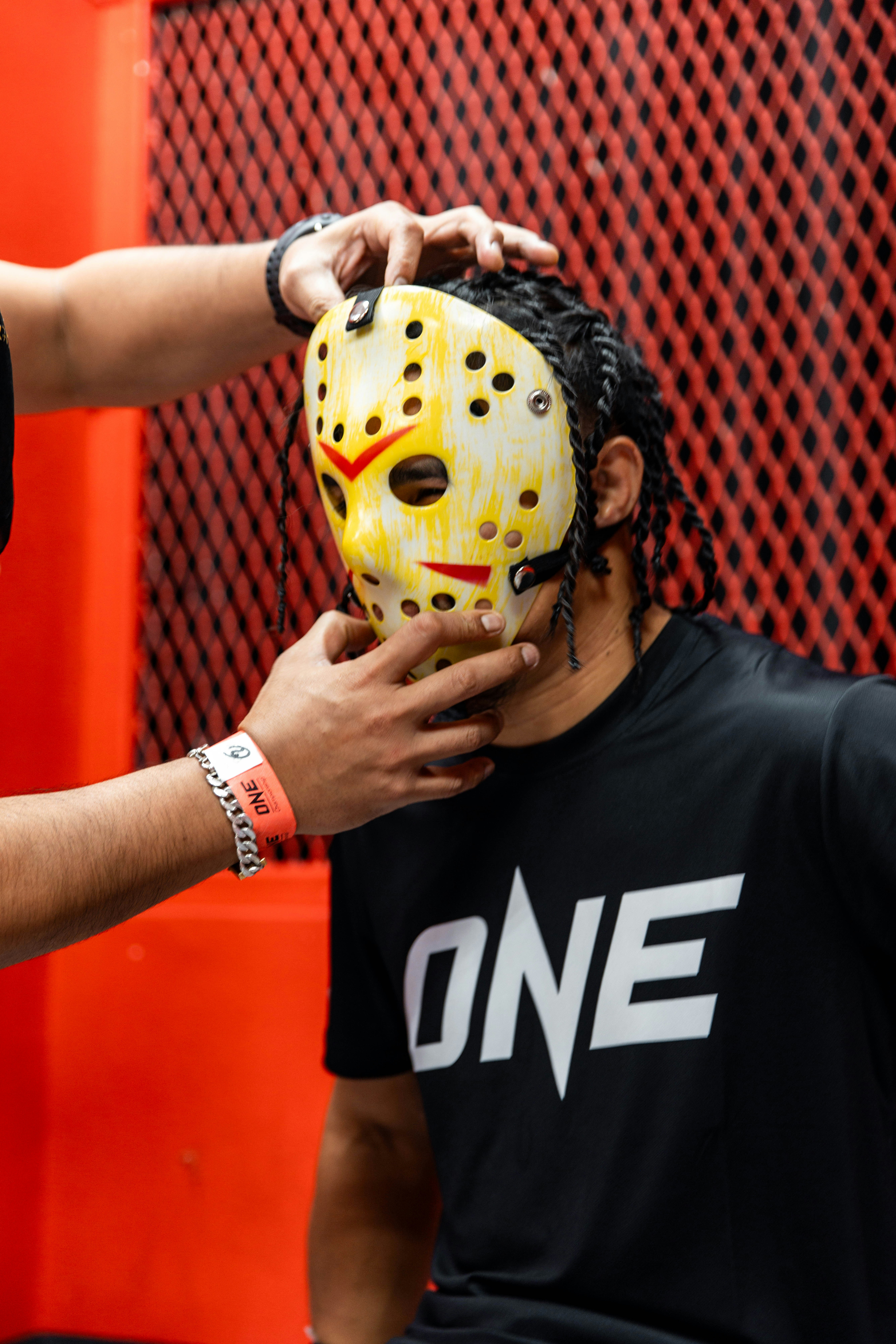 Person, die eine Hockeymaske über eine andere Person setzt.