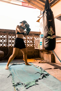 Woman boxing with a heavy bag in an outdoor gym.