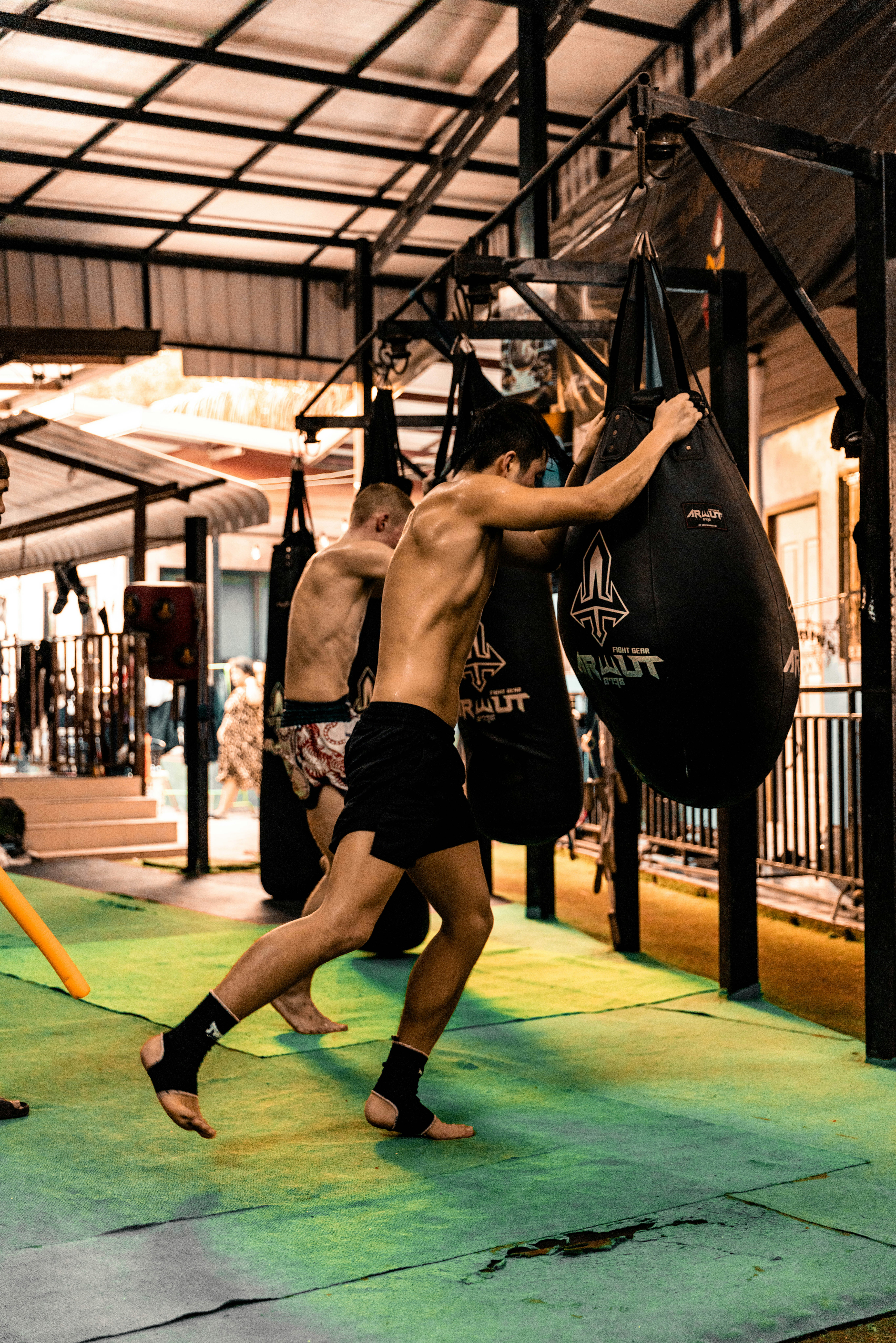 Zwei Männer, die mit schweren Taschen in einem Fitnessstudio trainieren.