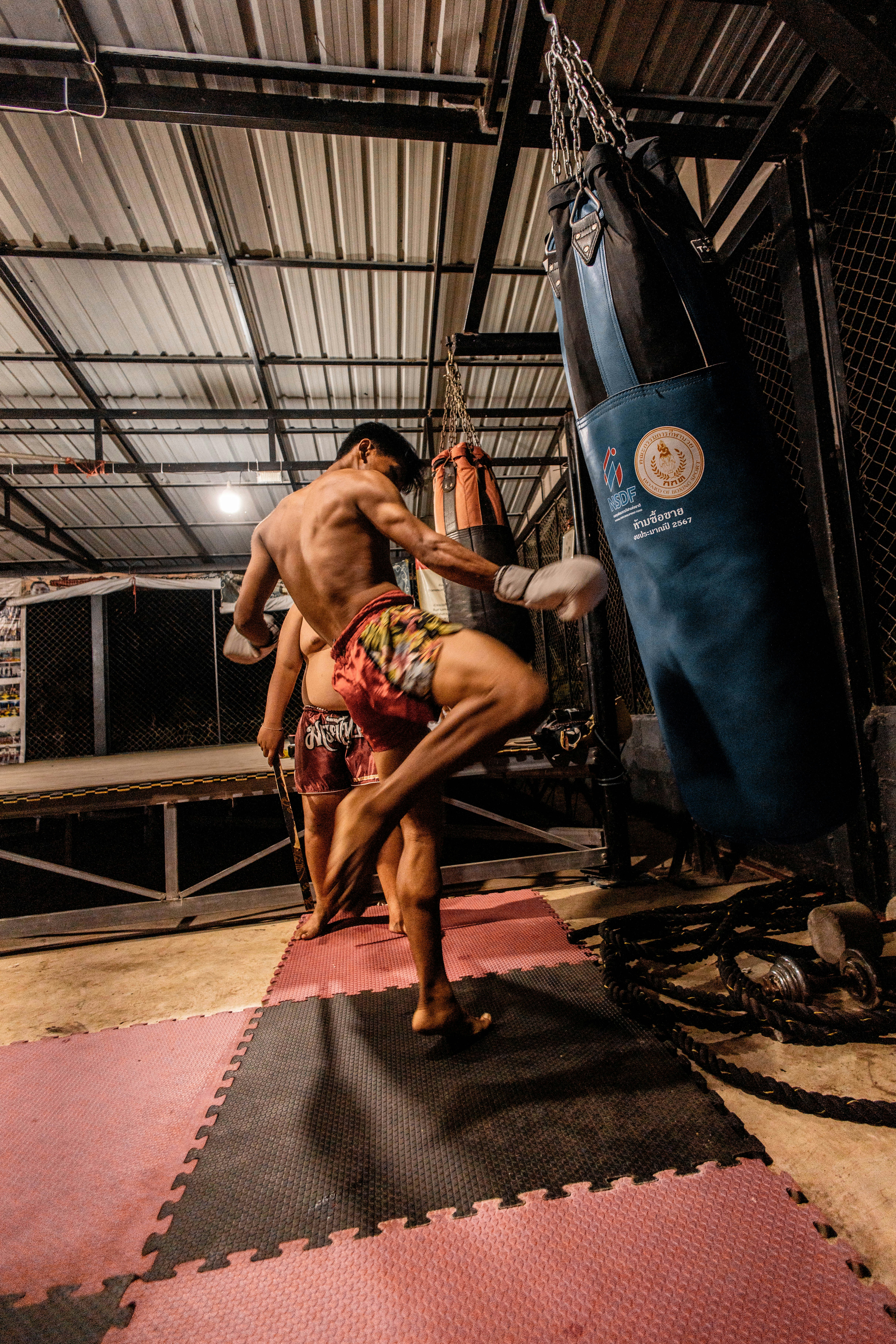 Man training muay thai with a punching bag.