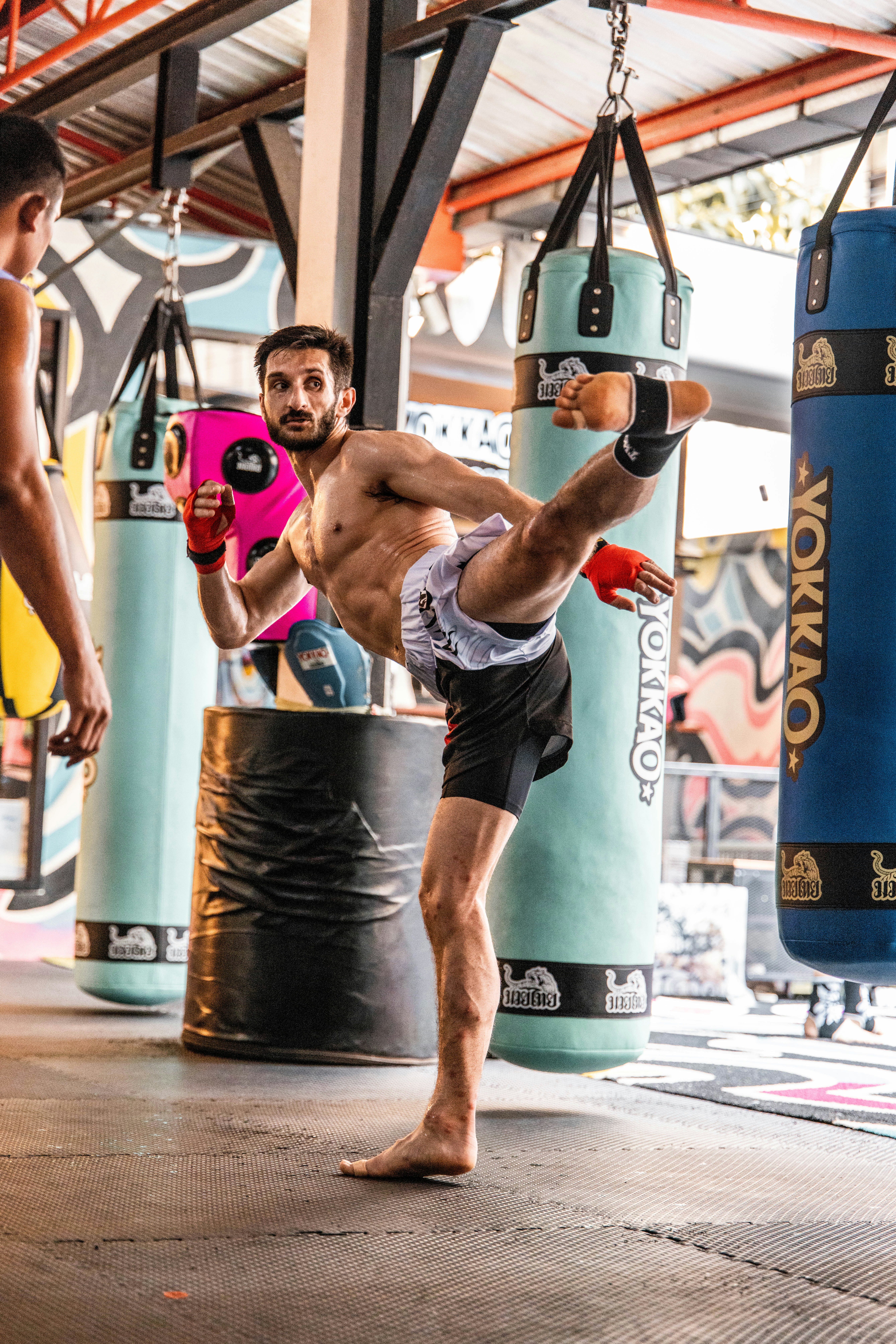 Ein Mann, der einen Muay Thai-Kick in einer Turnhalle übt.