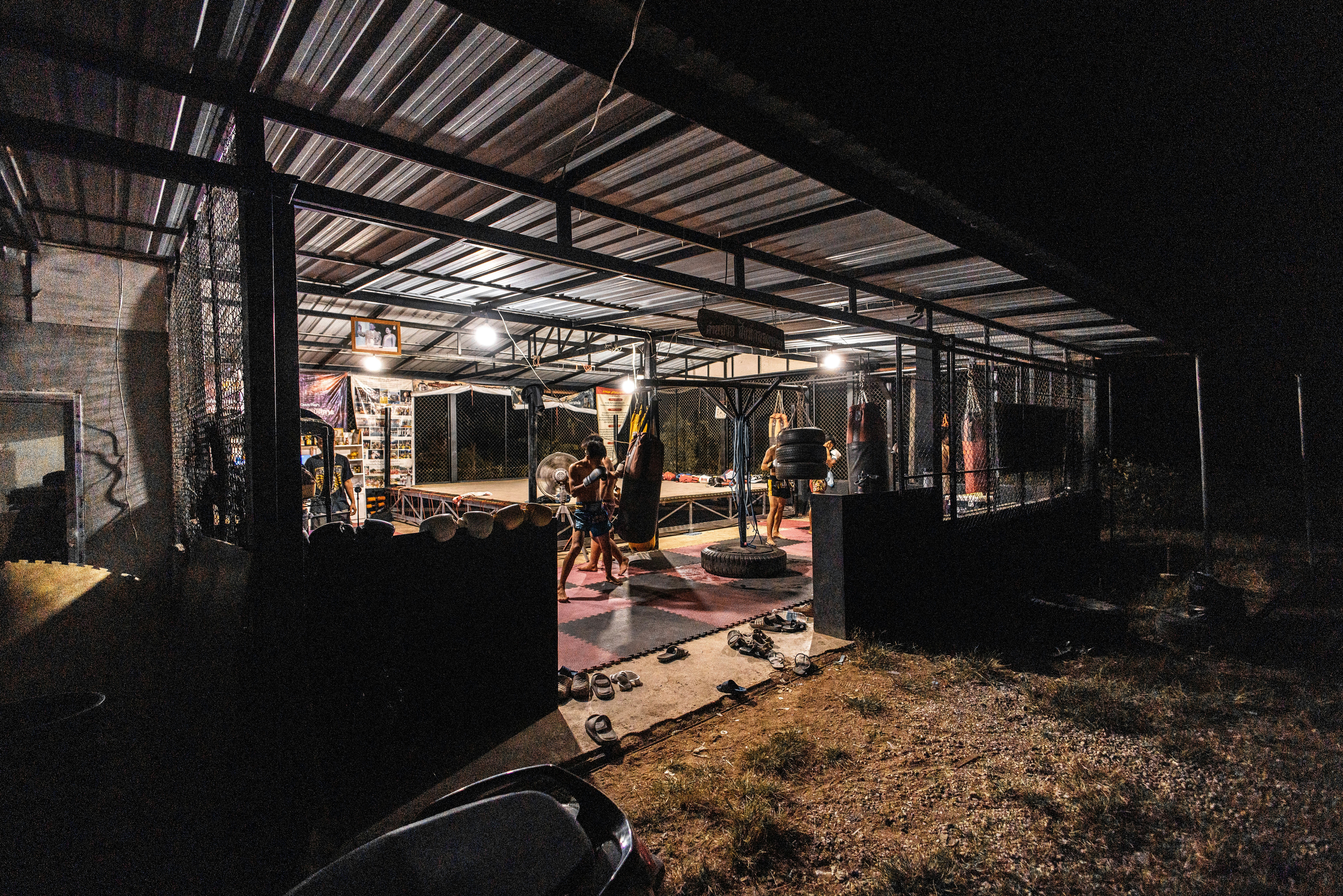 People exercising in a dimly lit outdoor gym at night.