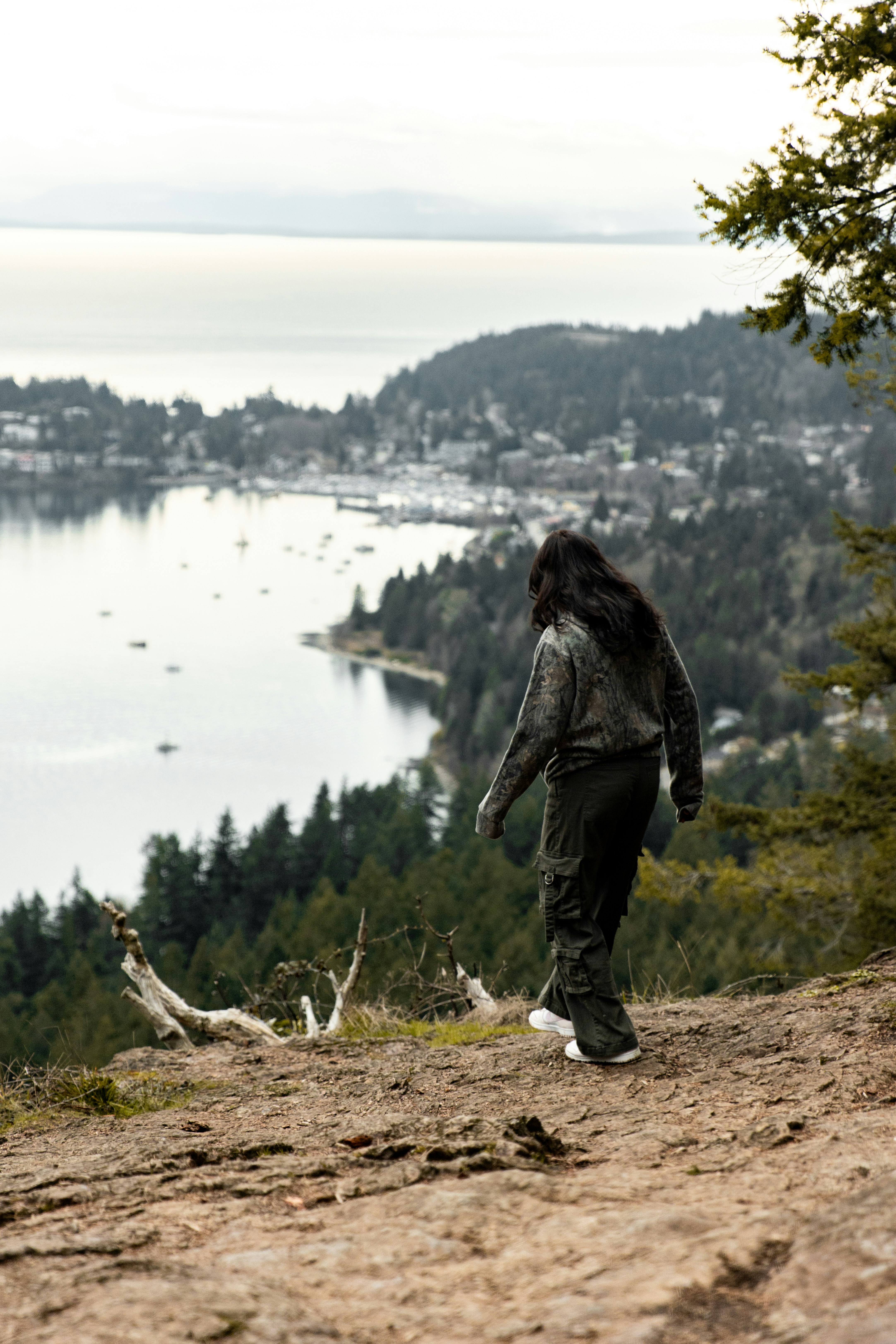 Frau, die auf einer Klippe mit Blick auf eine Bucht läuft.
