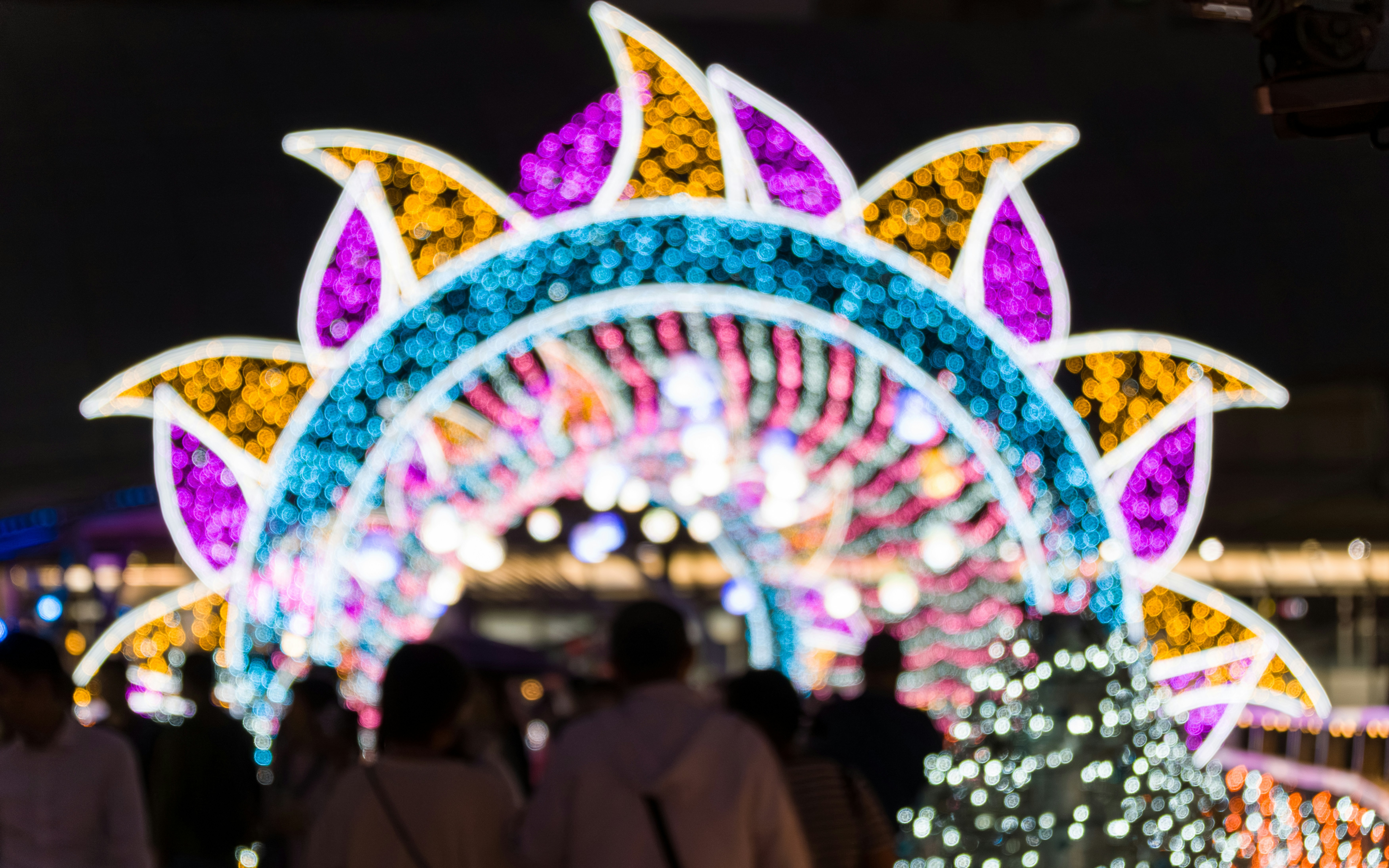 Colorful illuminated archway at night with people