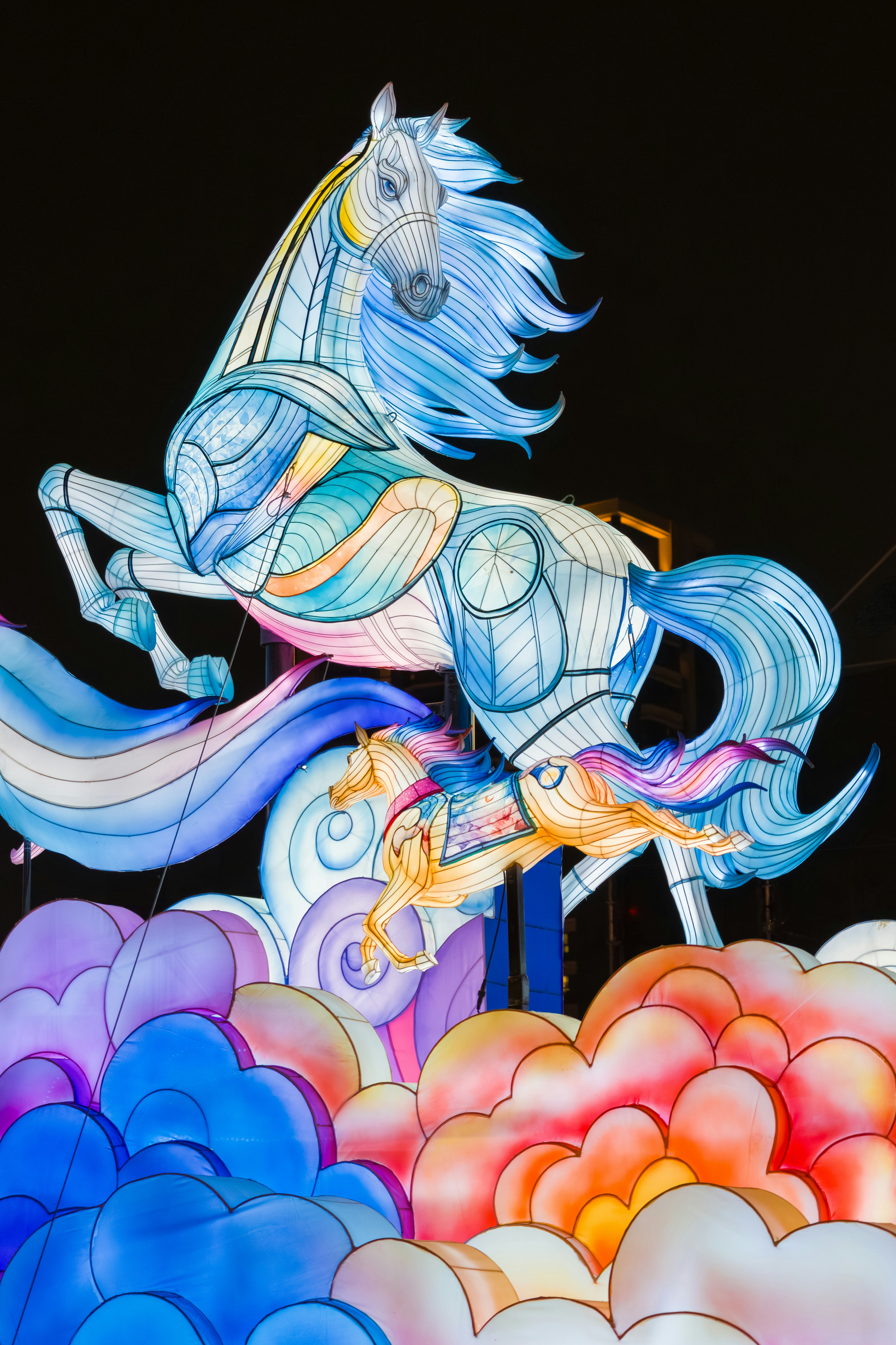 Colorful illuminated horse lanterns float on clouds at night