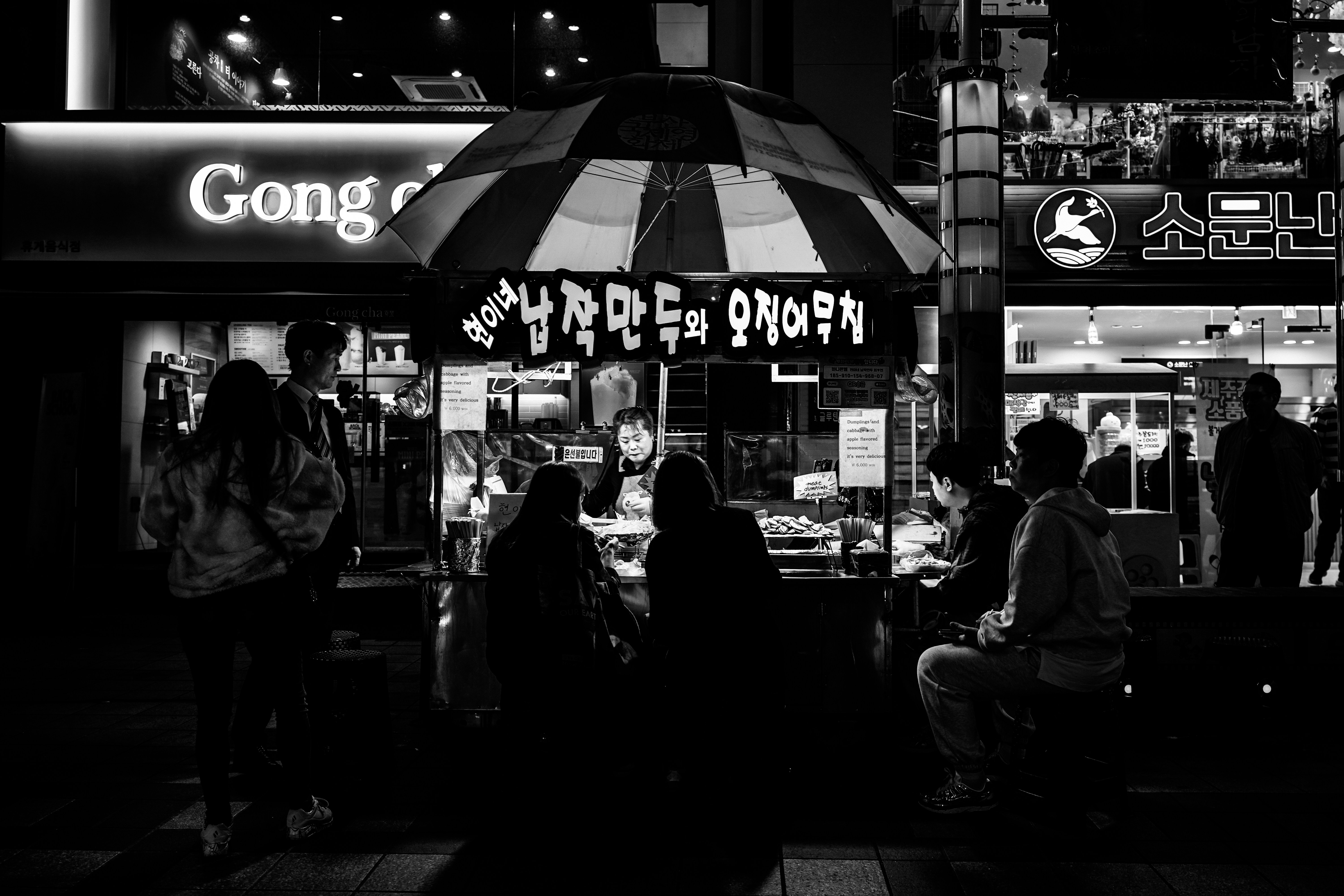 People gather at a night market food stall.