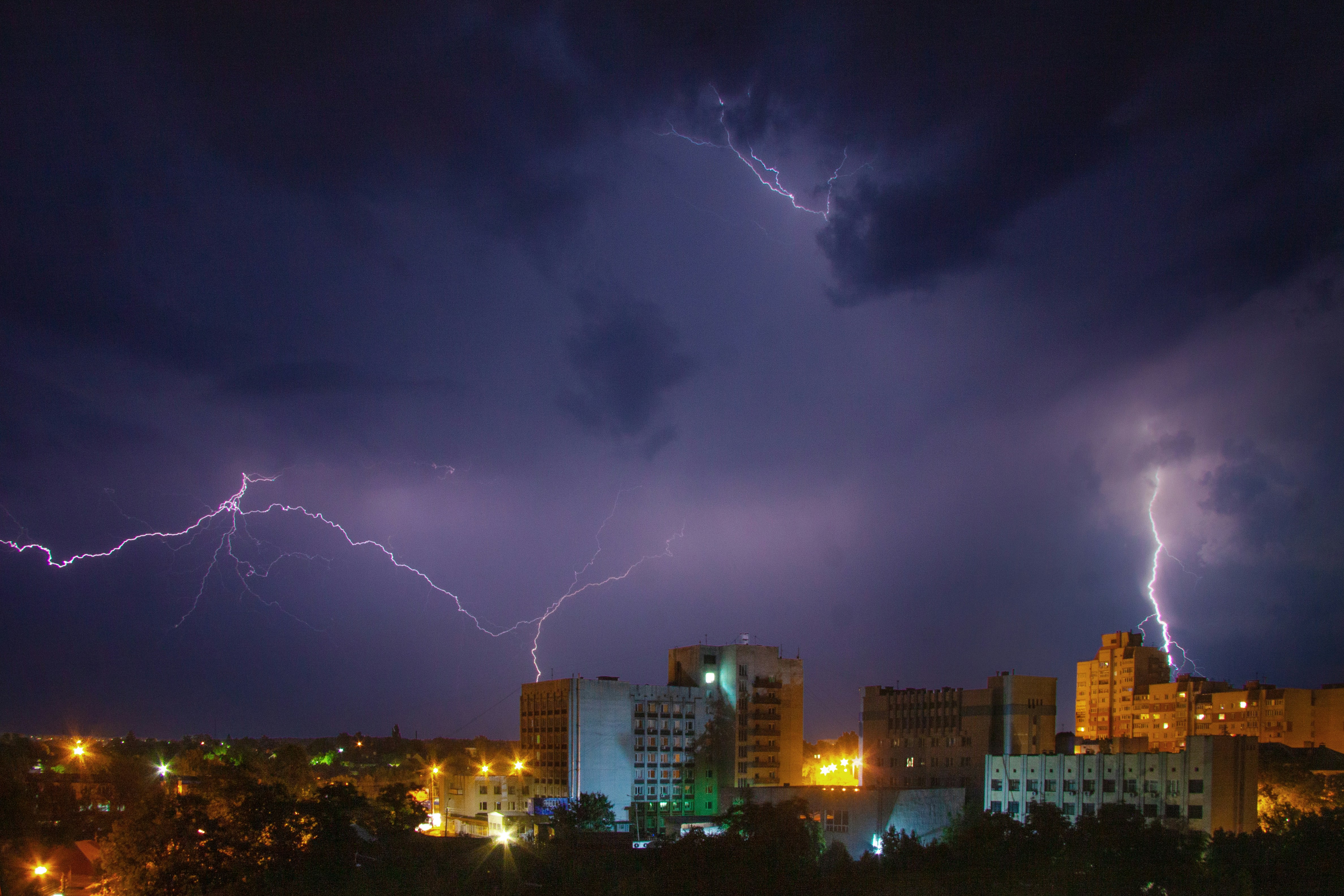 Des éclairs illuminent la silhouette d’une ville la nuit.