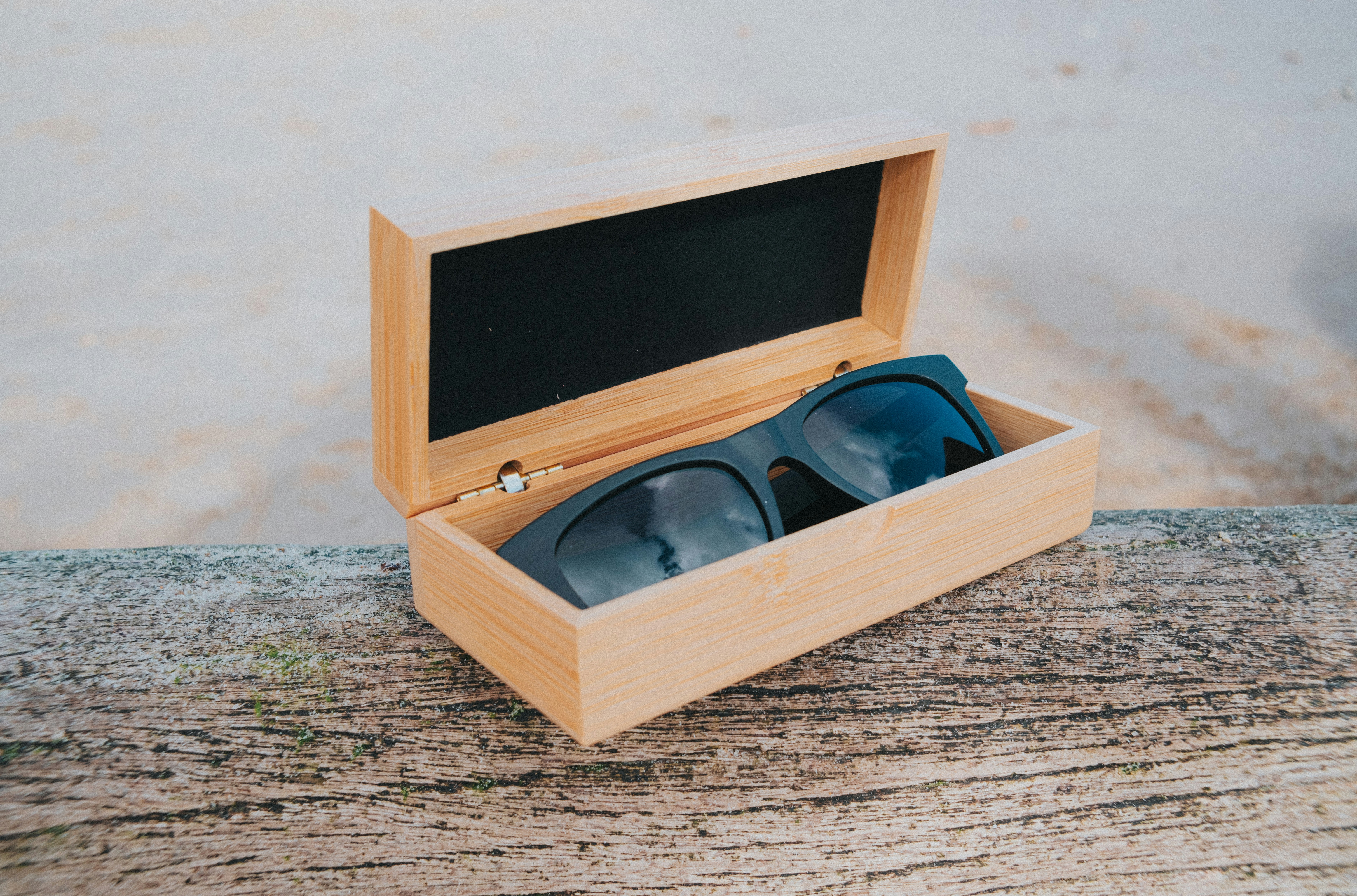 Occhiali da sole in una scatola di legno su una spiaggia