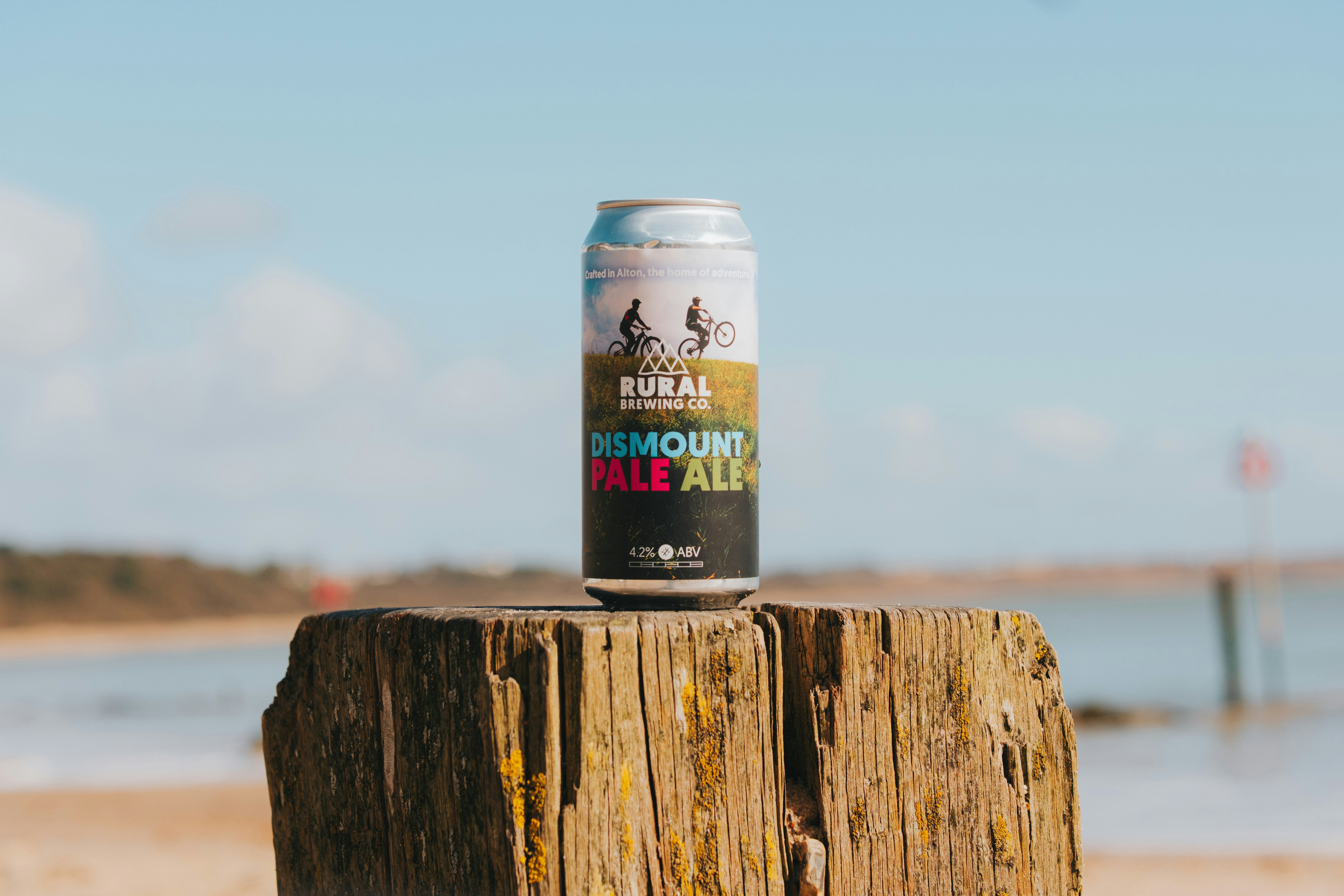 A can of ale sits on a weathered wooden post.