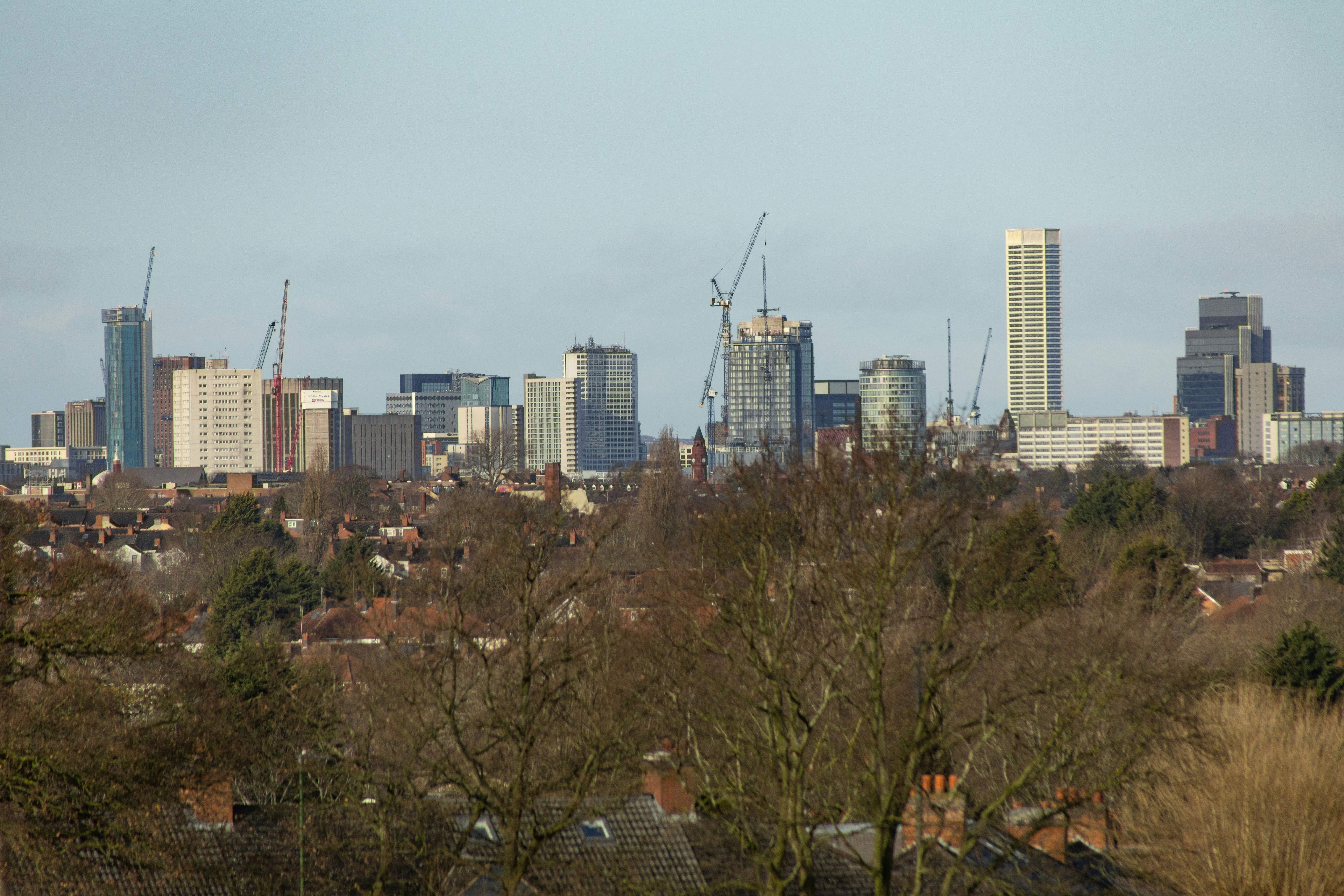 Modern cityscape with skyscrapers and construction cranes.