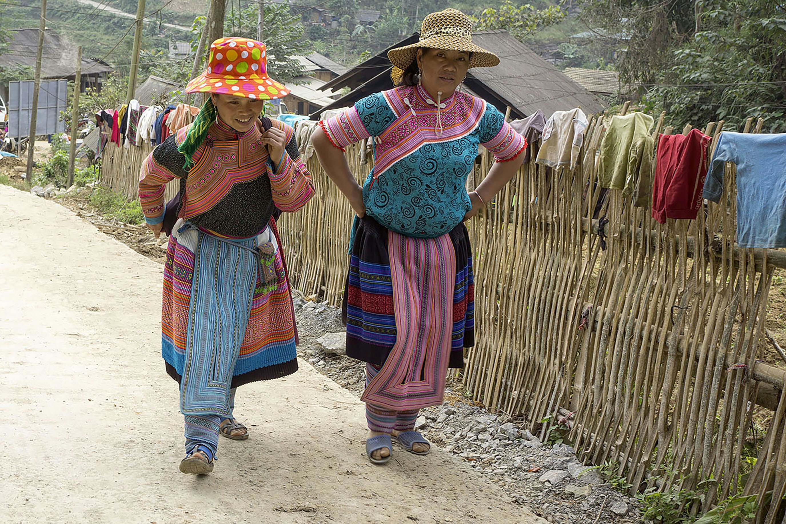 전통 의상을 입은 두 여성이 흙길을 걷고 있다.