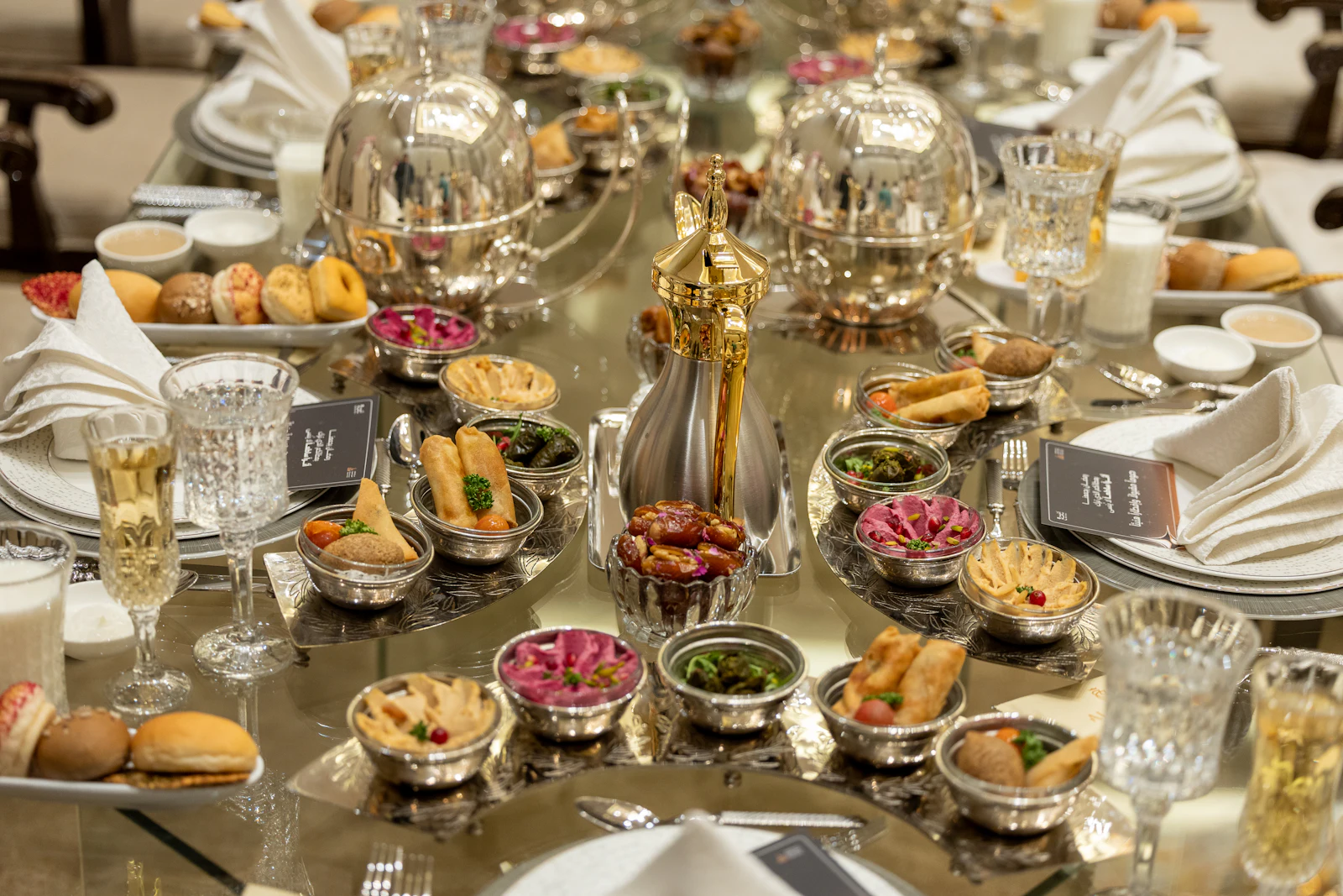 A long table laid with brass dishes and sweets for a community gathering.