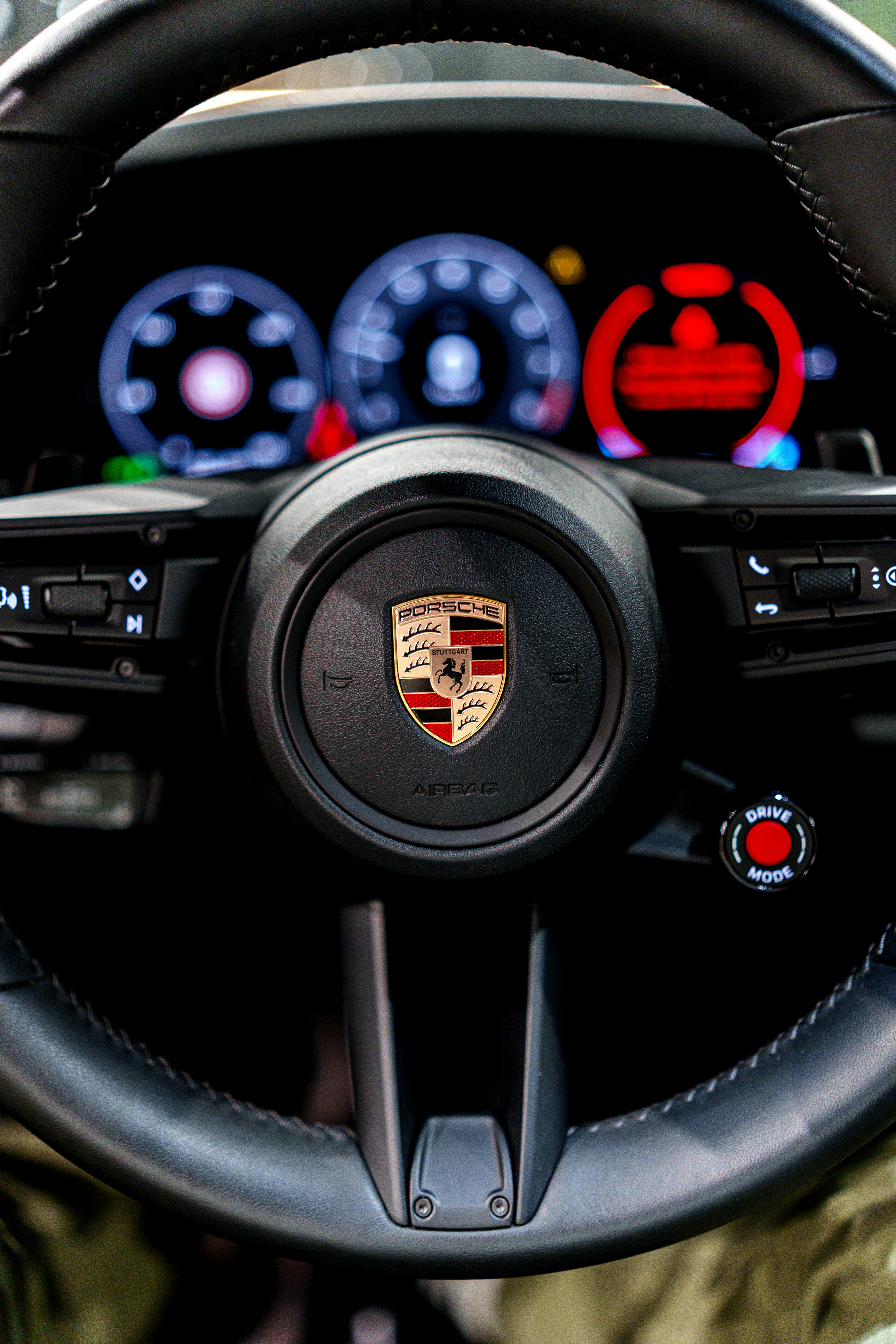 Close-up of a porsche steering wheel with illuminated dashboard.