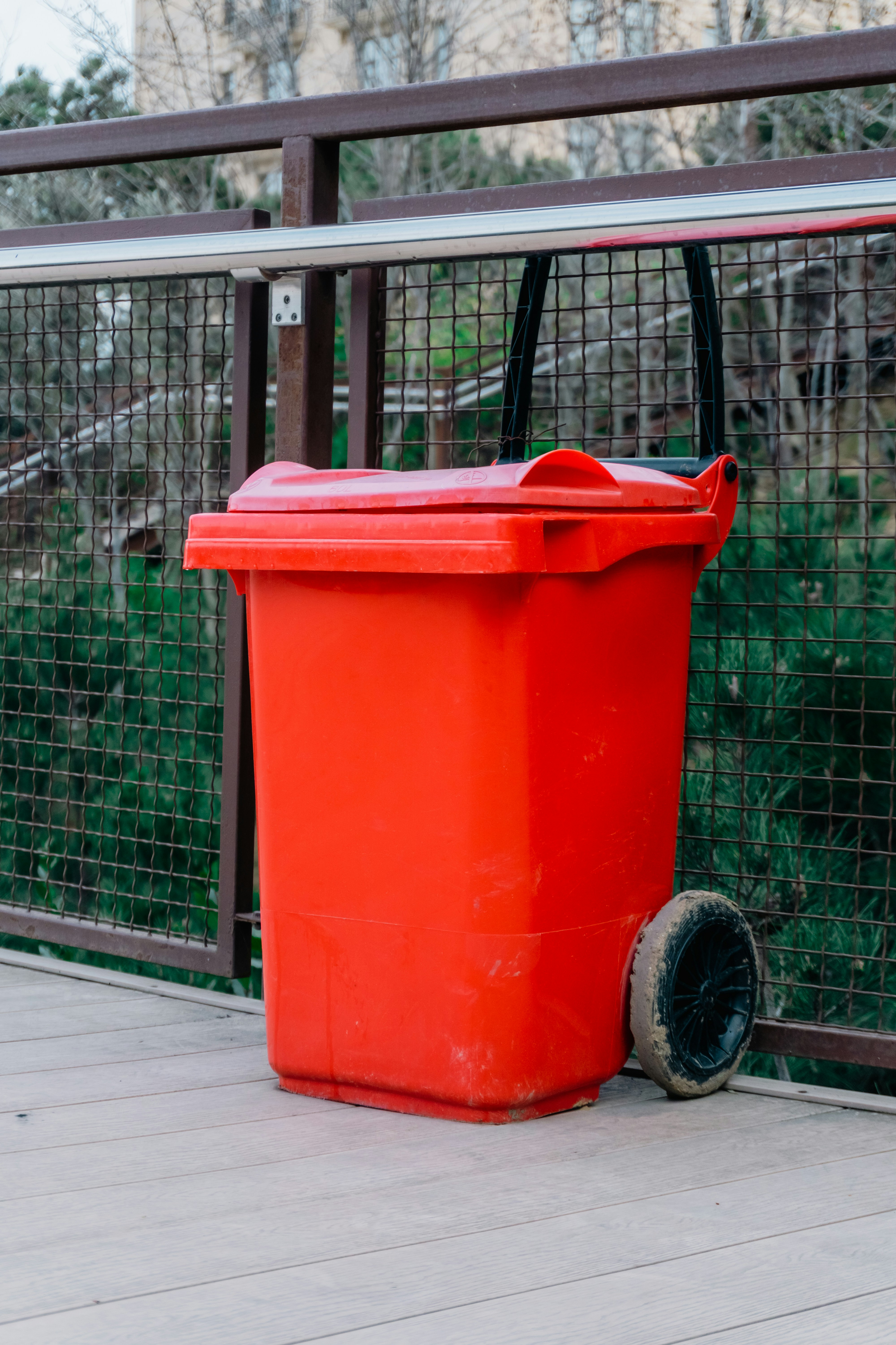 Une poubelle rouge vif avec des roues à l’extérieur.