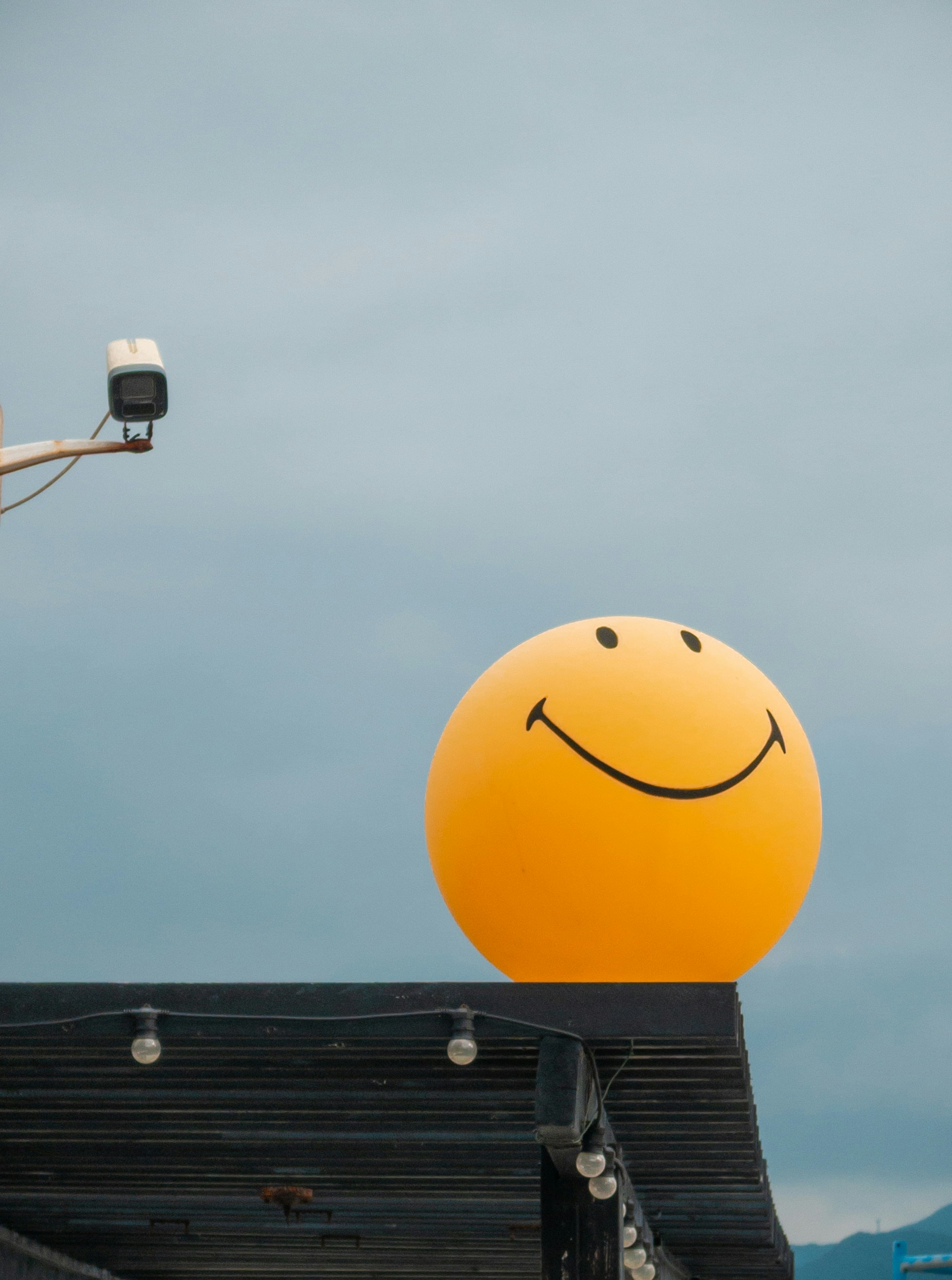 Un gran globo amarillo con una cara sonriente en una azotea.