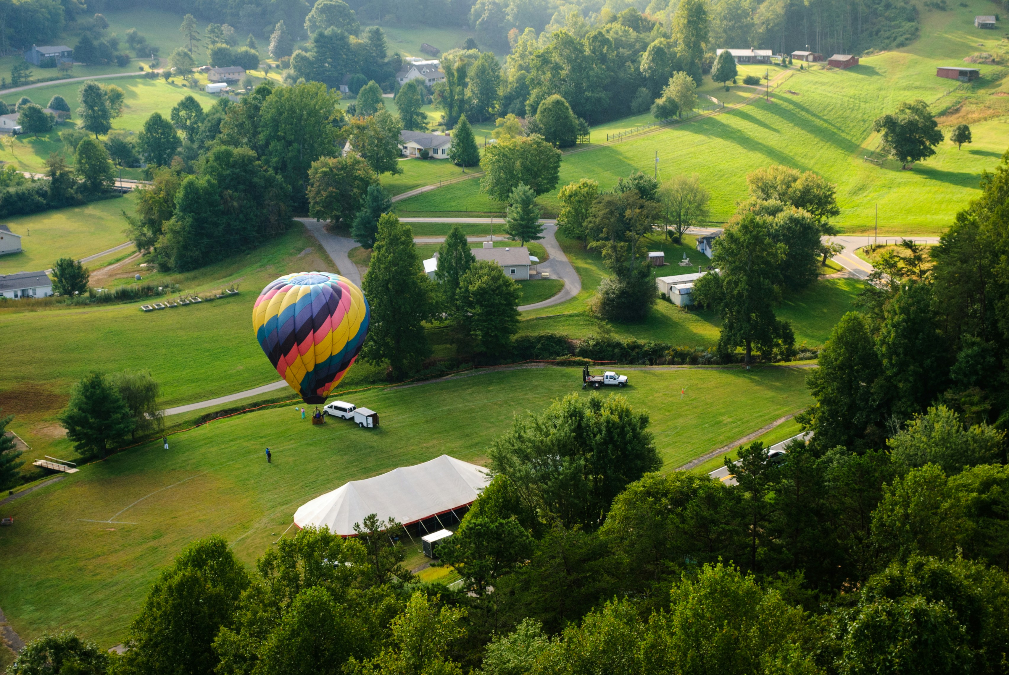 A colorful hot air balloon floats over a green valley.
