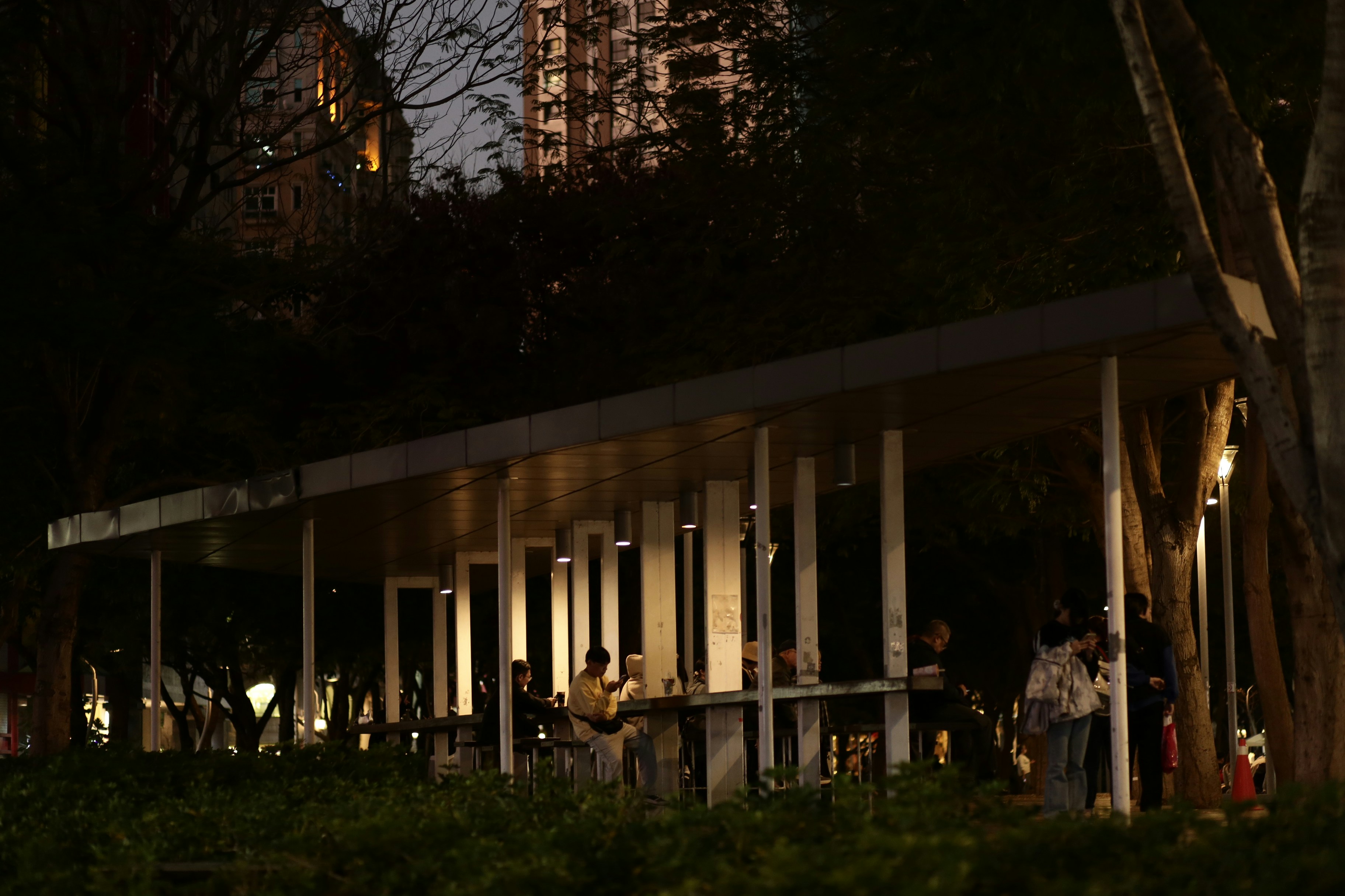People gathered at a modern pavilion at night.