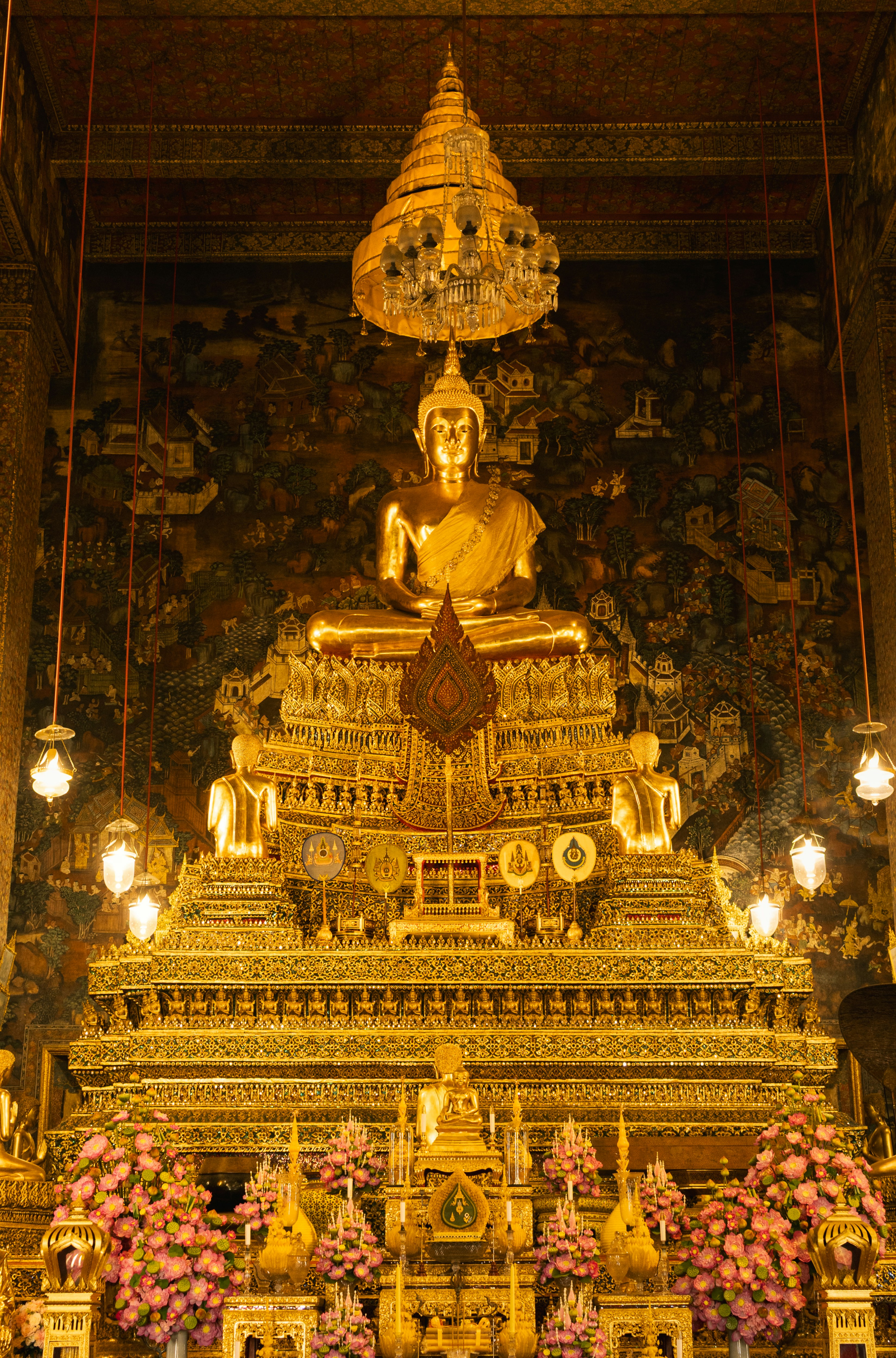 Estatua dorada de Buda sentada en un trono ornamentado con flores