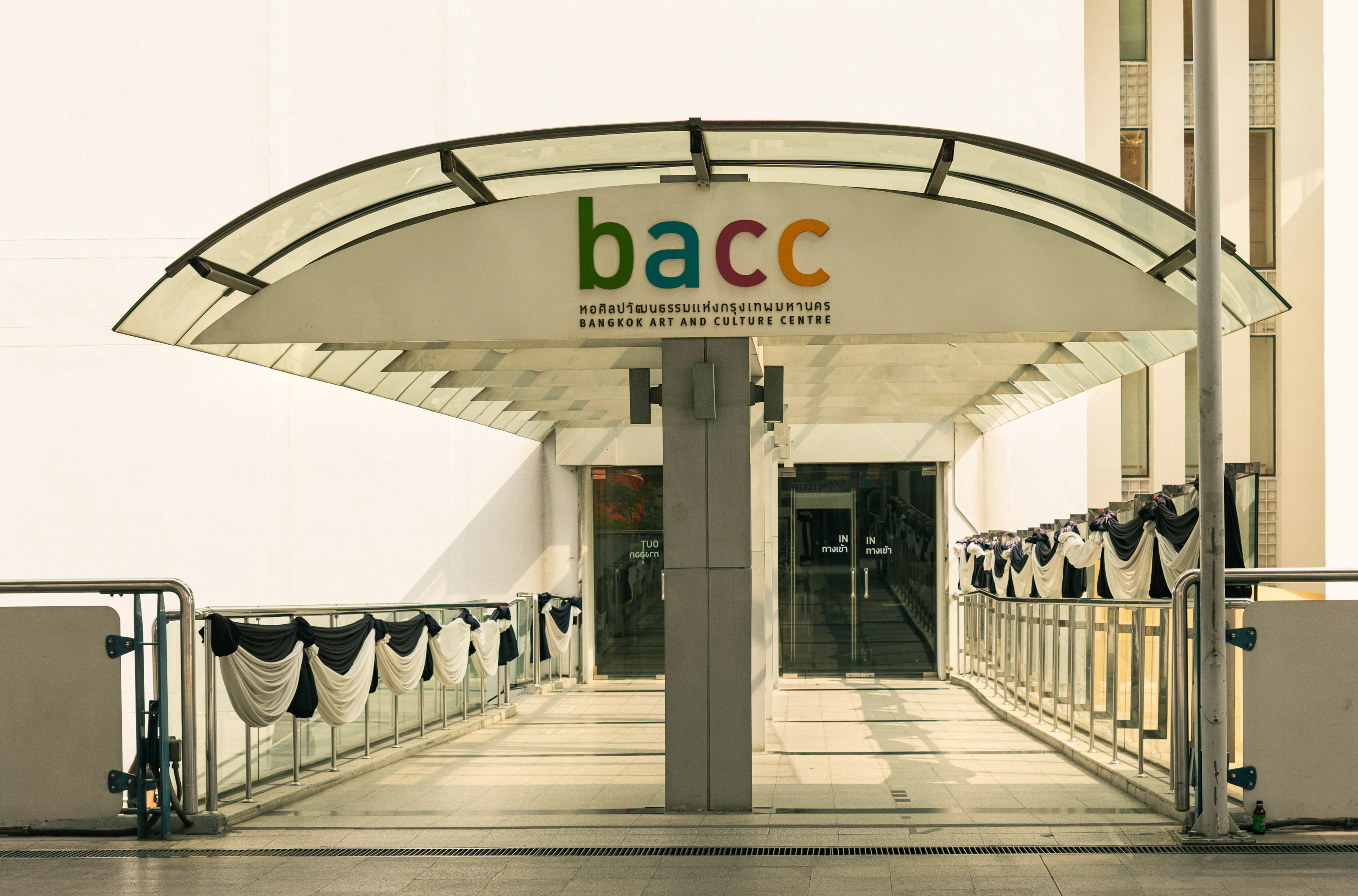 The curved glass entrance canopy of the Bangkok Art and Culture Centre, its lettering above the doors