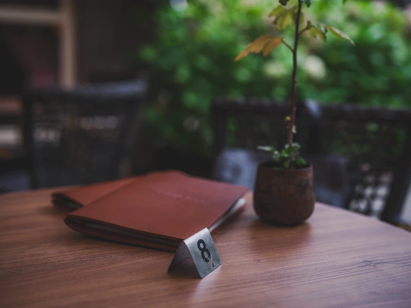Table number eight with menus and potted plant.