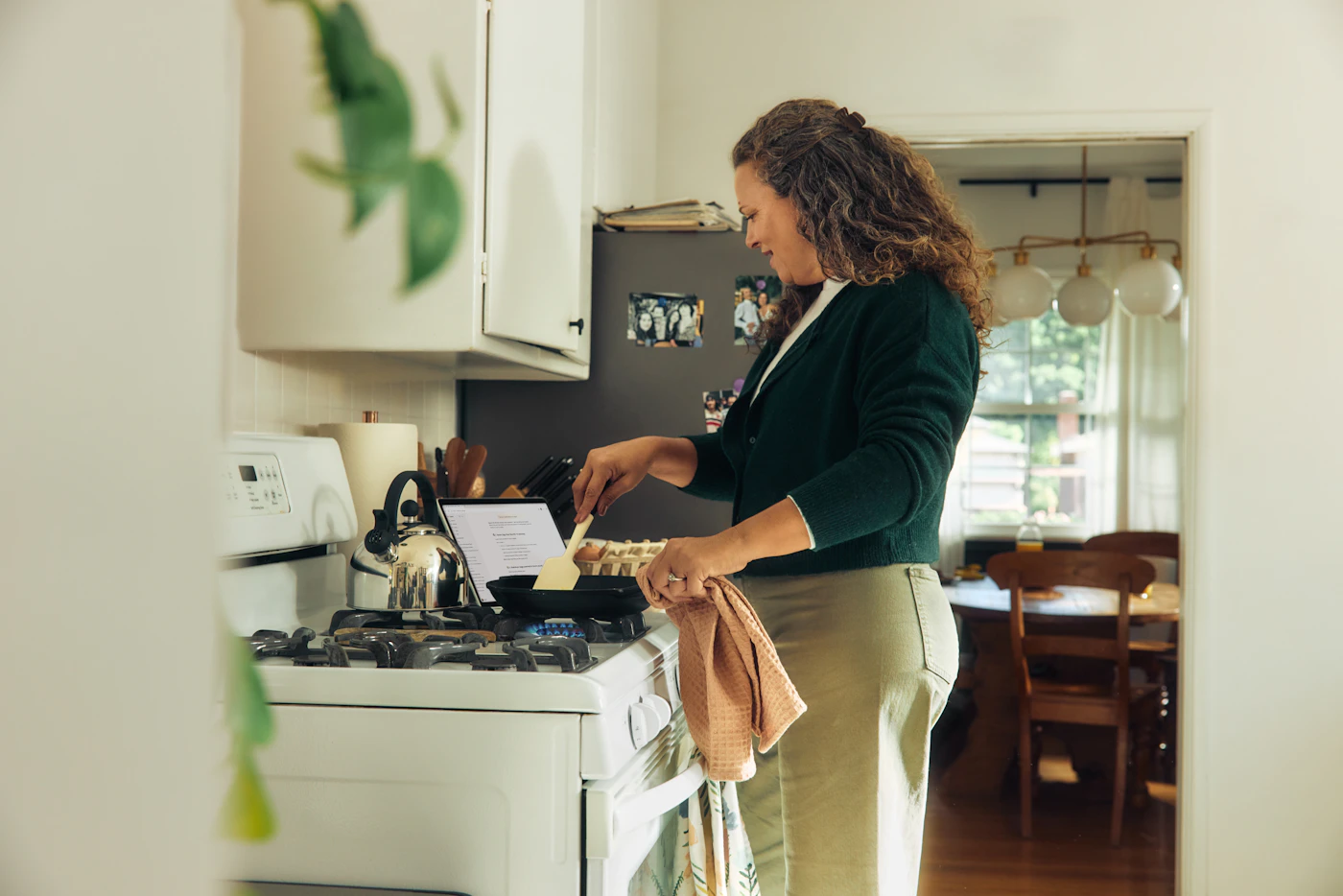 A woman with curly hair cooking at the stove in her home kitchen