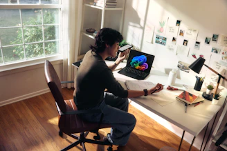 Person working at a desk with a laptop and books.