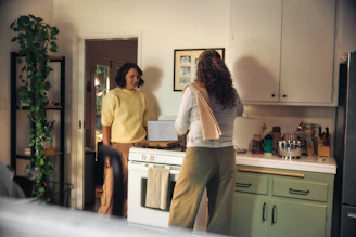 Two women talking in a kitchen while cooking
