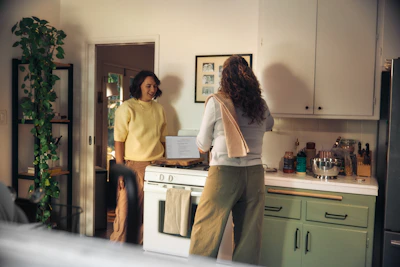 Two women talking in a kitchen while cooking
