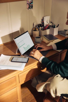 Person working on laptop at a wooden desk