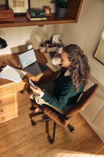 Woman working at a desk with laptop and tablet.