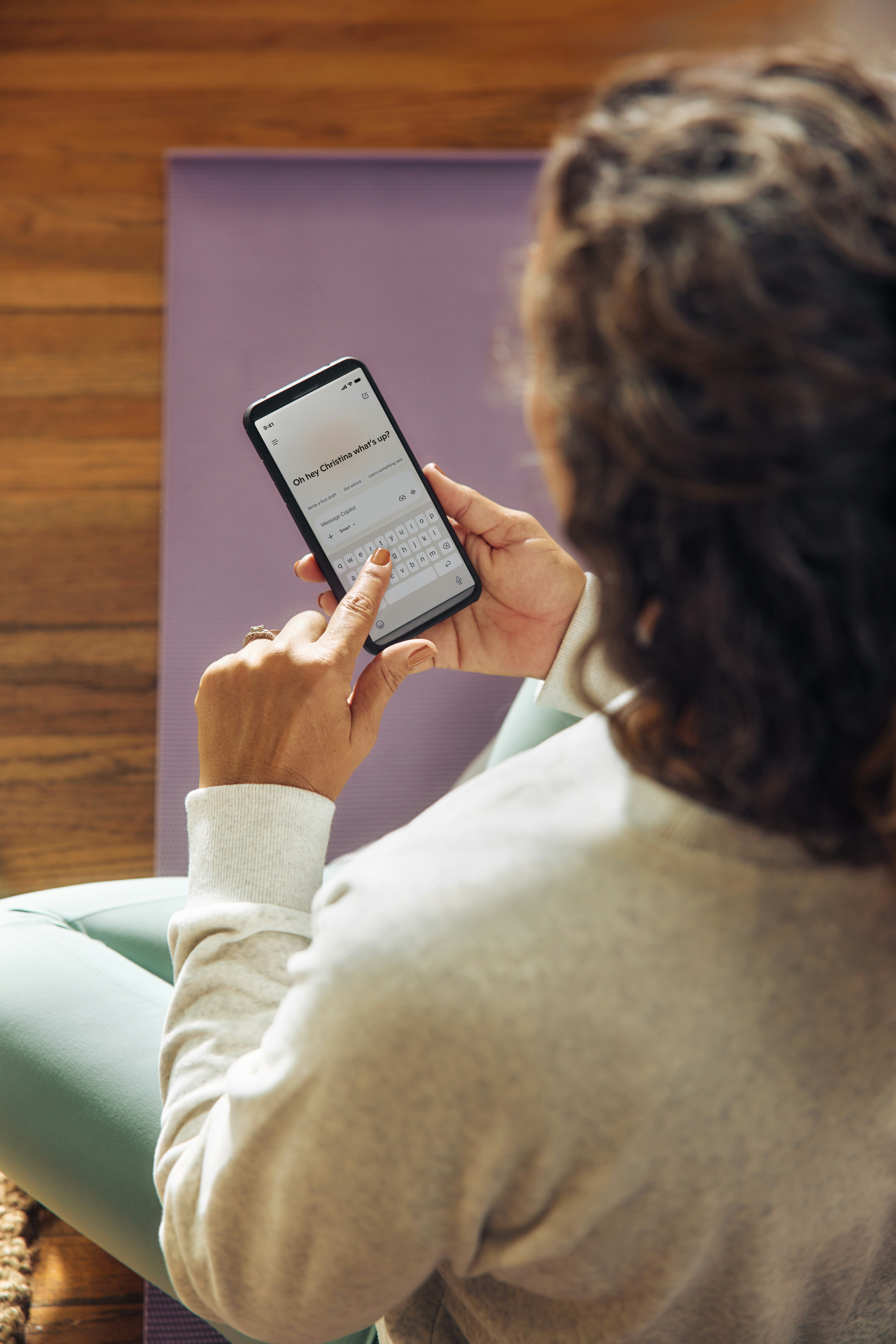 Woman using a smartphone on a yoga mat.