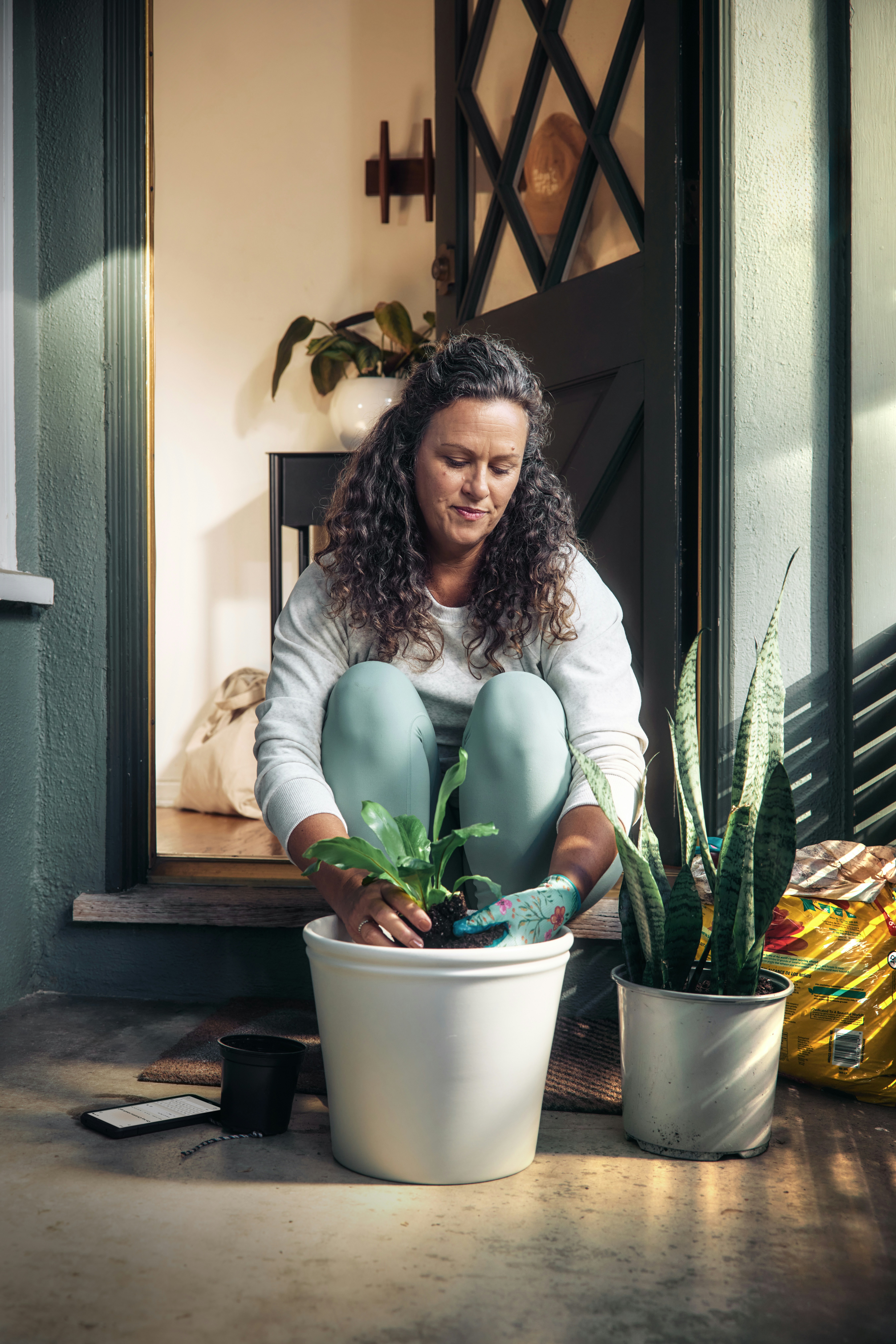 Woman potting a plant on a porch - 相关推荐