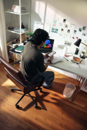 Man working at desk with laptop and phone.
