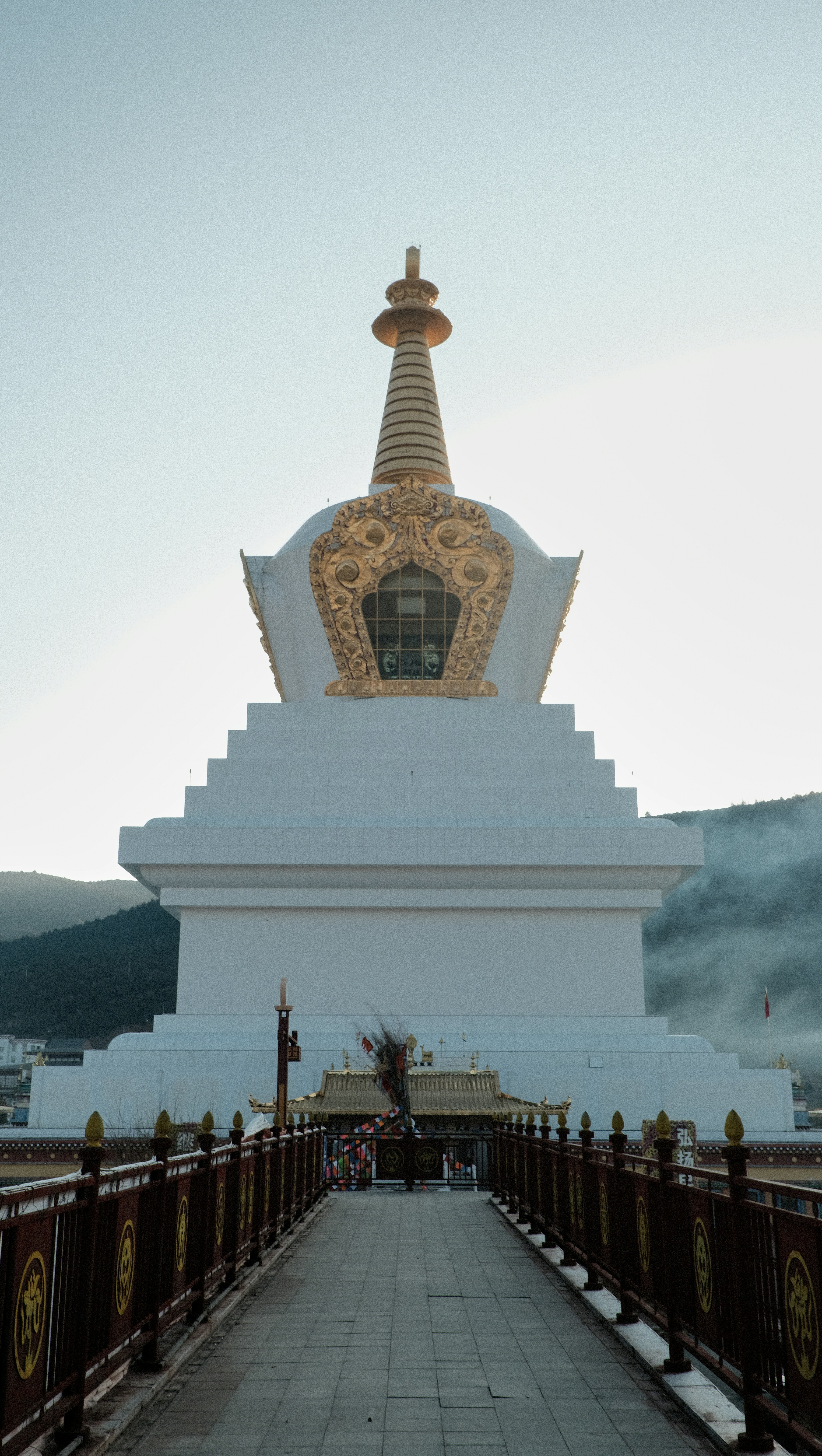 White stupa with golden ornamentation against a clear sky.