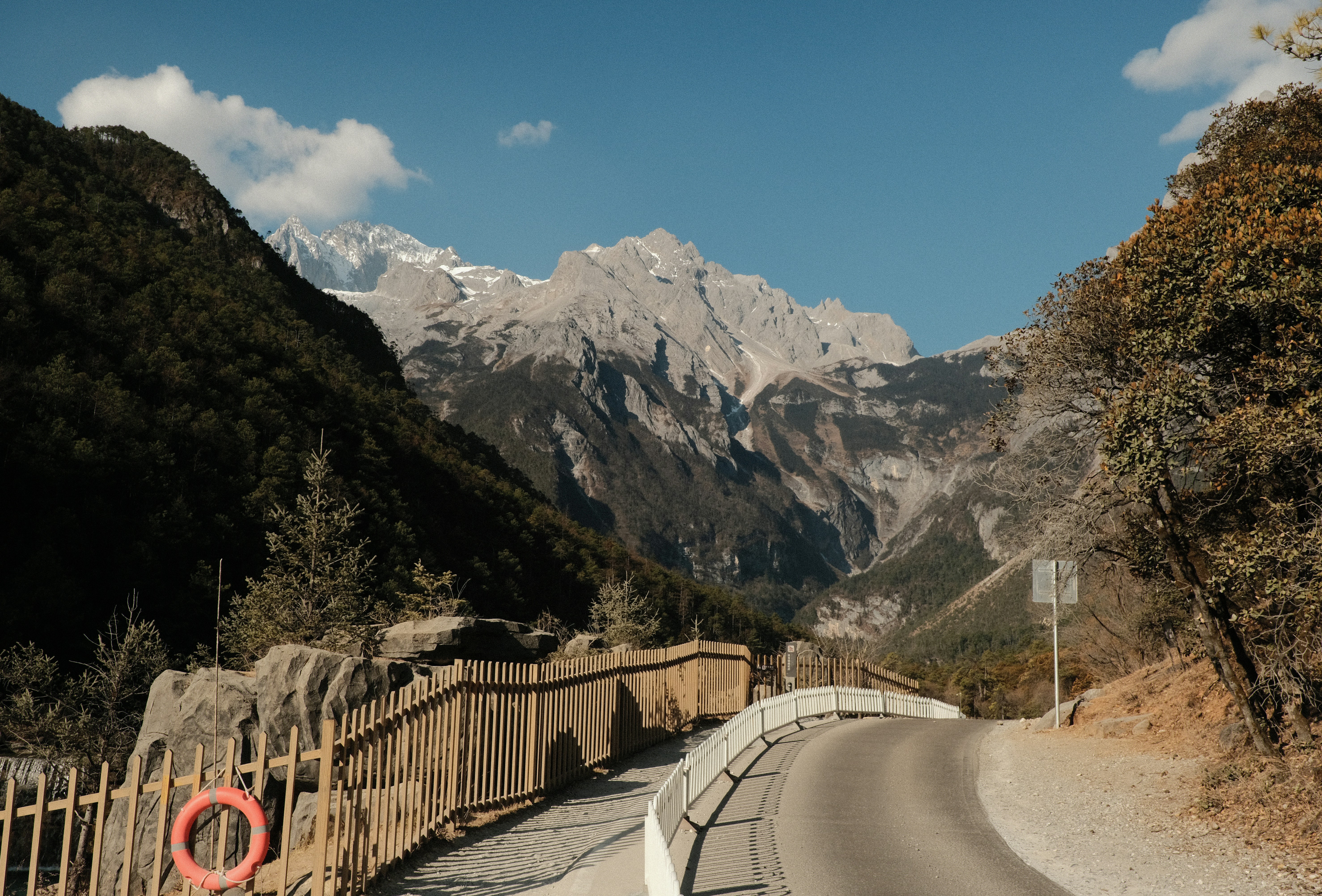 Road leading to majestic snow-capped mountains under a blue sky