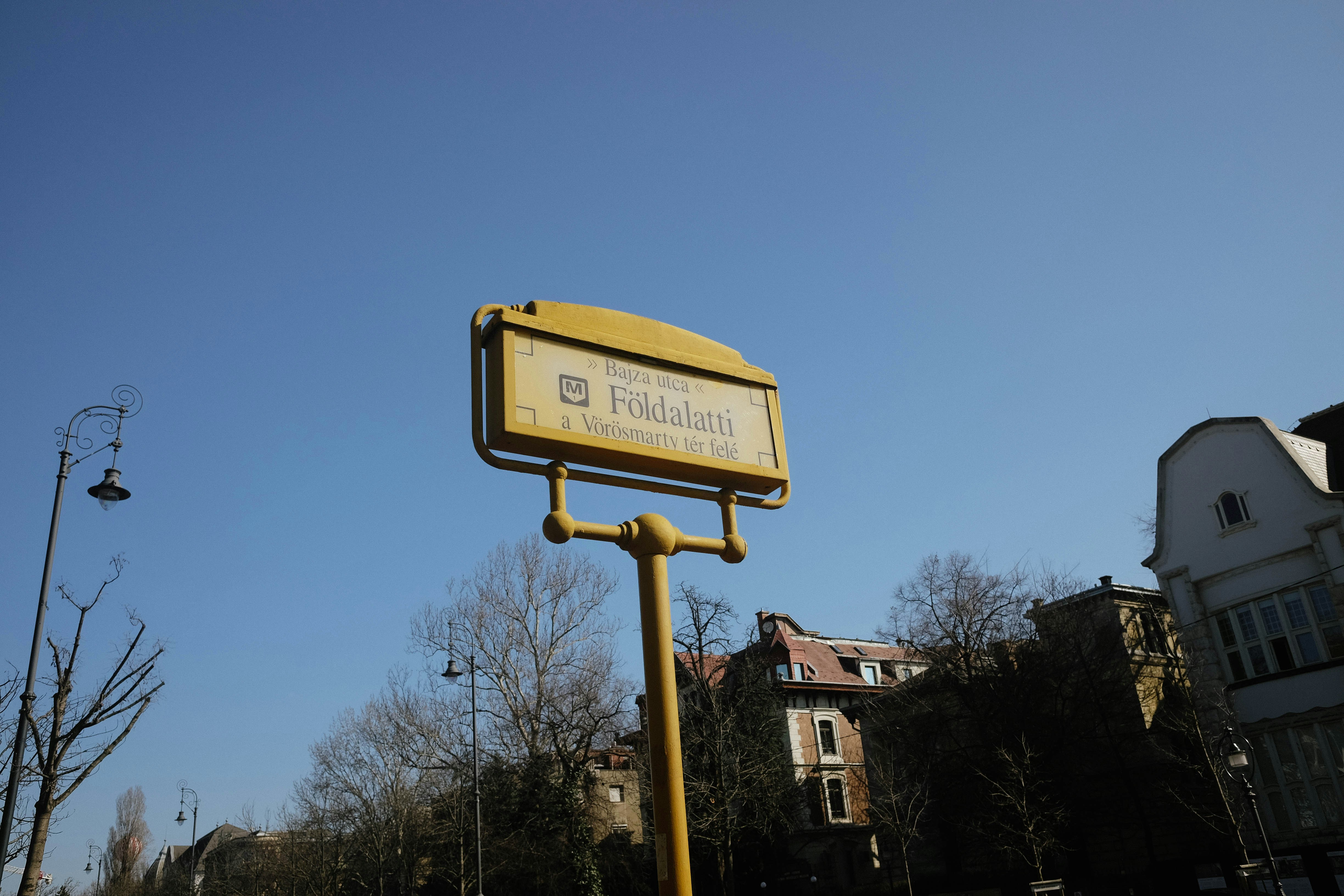Yellow street sign with text against blue sky