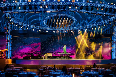 A performer plays piano on a brightly lit stage
