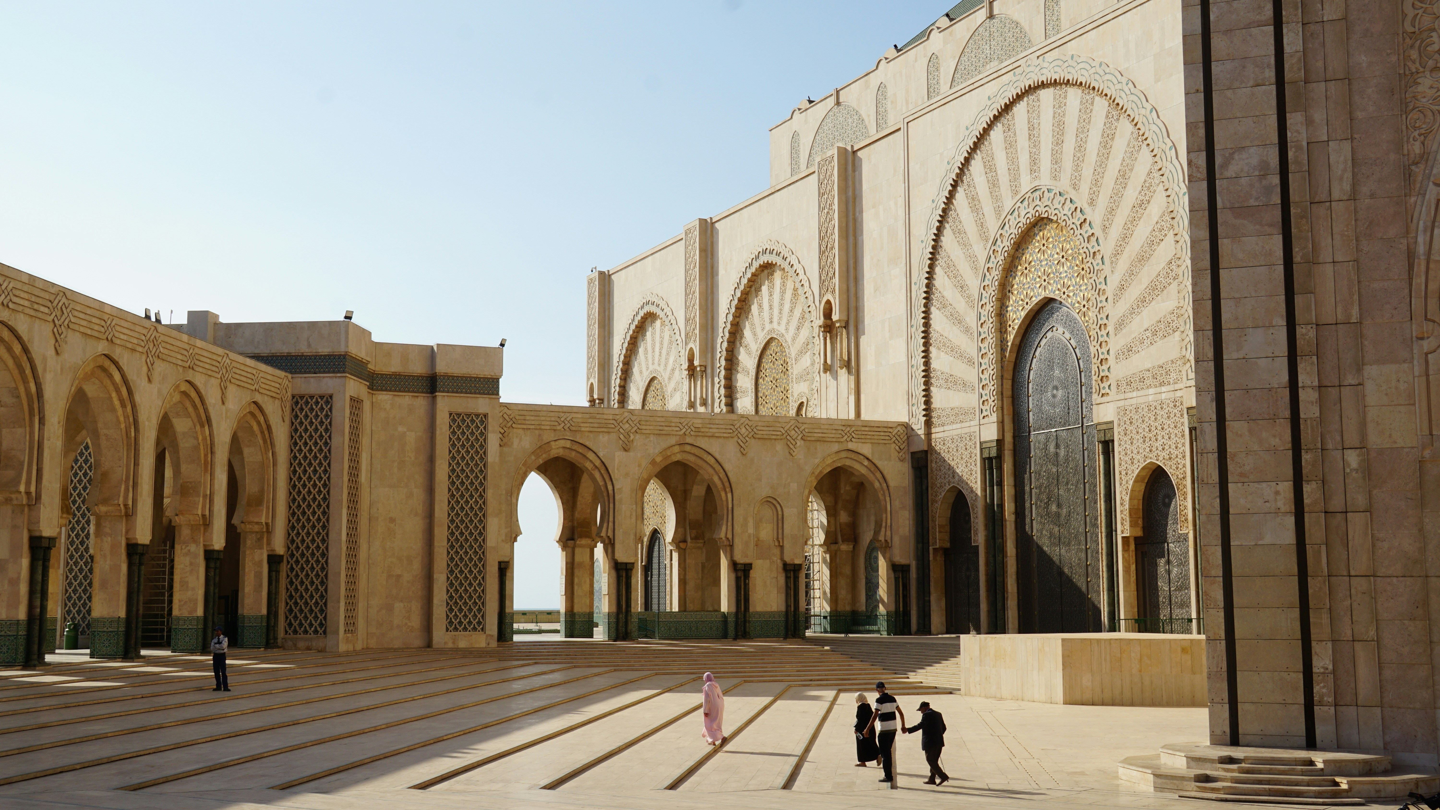People walking in a courtyard of a large mosque.