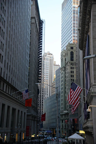 Tall buildings line a street with american flags.